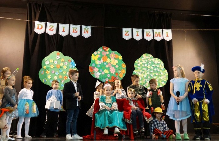 21 kwietnia 2023 roku w naszej szkole odbył się apel poświęcony problematyce segregacji odpadów. Uczniowie z klas drugich i trzecich, a następnie dzieci z grup przedszkolnych, z wielkim zainteresowaniem obejrzeli sztukę o tarapatach w Królestwie Jego  Królewskiej  Mości, Króla Surowca Wtórnego. Niedobrze żyło się poddanym w tym zaśmieconym Królestwie. Ludzie nie dbali o porządek, rzucali zbędne opakowania byle gdzie, szklane butelki zostawiali w lesie, a metalowe puszki w parku pod ławką. Poddani zwrócili się do Króla Surowca Wtórnego o pomoc w rozwiązaniu tego problemu. Rozwiązanie znaleźli  najmłodsi członkowie rodziny królewskiej: Królewicz Surowczyk i Królewna Surówka. Zaproponowali segregację odpadów w królestwie, poprzez ustawienie koszy na ulicach z napisami, co wrzucać do którego kosza. Wszystkim zebranym pomysł się bardzo spodobał .Humorystyczna tematyka apelu uwrażliwiła naszych uczniów na problem segregacji odpadów we własnych rodzinach, możliwości ograniczenia ilości wytwarzanych śmieci oraz dbałości o najbliższe otoczenie.   Aktorami przedstawienia byli uczniowie klas: IA i IB pod kierunkiem wychowawczyń: Danuty Prokop i Ewy Kilian.