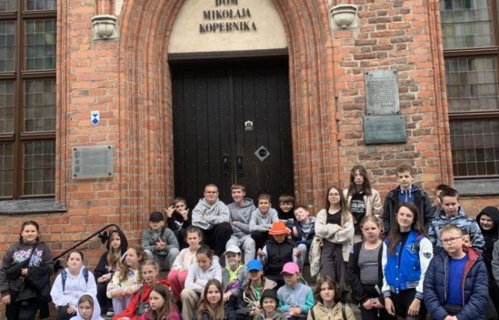 19 maja uczniowie klas 5a i 5b odwiedzili rodzinne miasto Mikołaja Kopernika. Zwiedzanie Torunia rozpoczęliśmy od Krzywej Wieży. Tutaj mogliśmy sprawdzić naszą prawość i uczciwość, gdyż według legendy tylko człowiek bez grzechu może utrzymać równowagę opierając się o jej ścianę. Następnie pan przewodnik oprowadził nas po Starym Mieście. Zobaczyliśmy dom i pomnik Mikołaja Kopernika, podziwialiśmy gotyckie kamienice, Bramę Klasztorną, Ratusz Staromiejski, Katedrę św. Jana Chrzciciela i św. Jana Ewangelisty. Poznaliśmy historię miasta i losy Mikołaja Kopernika. 
Kolejnym punktem programu było Żywe Muzeum Piernika. Pod okiem mistrza Dawida poznaliśmy rytuały związane z wypiekiem piernika. Własnoręcznie przygotowaliśmy ciasto i przy użyciu drewnianych form upiekliśmy pierniczki. Po warsztatach mieliśmy okazję zobaczyć manufakturę z początku XX wieku, maszyny służące do wypieku piernika, zabytkowy piec oraz kolekcję form woskowych.
Ostatnią atrakcją był Dom Legend Toruńskich. Tutaj nie tylko wysłuchaliśmy legend związanych z miastem, ale również sami mogliśmy wcielić się w ich bohaterów.
W drodze powrotnej zajechaliśmy do Grudziądza. Przeszliśmy Bramą Wodną na Stare Miasto i zrobiliśmy pamiątkową fotografię pod pomnikiem ułana i dziewczyny. 
To był udany dzień, pełen wrażeń. 