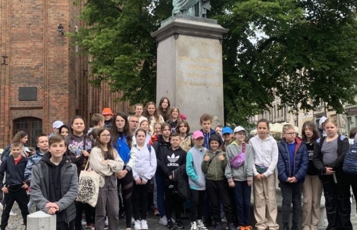 19 maja uczniowie klas 5a i 5b odwiedzili rodzinne miasto Mikołaja Kopernika. Zwiedzanie Torunia rozpoczęliśmy od Krzywej Wieży. Tutaj mogliśmy sprawdzić naszą prawość i uczciwość, gdyż według legendy tylko człowiek bez grzechu może utrzymać równowagę opierając się o jej ścianę. Następnie pan przewodnik oprowadził nas po Starym Mieście. Zobaczyliśmy dom i pomnik Mikołaja Kopernika, podziwialiśmy gotyckie kamienice, Bramę Klasztorną, Ratusz Staromiejski, Katedrę św. Jana Chrzciciela i św. Jana Ewangelisty. Poznaliśmy historię miasta i losy Mikołaja Kopernika. 
Kolejnym punktem programu było Żywe Muzeum Piernika. Pod okiem mistrza Dawida poznaliśmy rytuały związane z wypiekiem piernika. Własnoręcznie przygotowaliśmy ciasto i przy użyciu drewnianych form upiekliśmy pierniczki. Po warsztatach mieliśmy okazję zobaczyć manufakturę z początku XX wieku, maszyny służące do wypieku piernika, zabytkowy piec oraz kolekcję form woskowych.
Ostatnią atrakcją był Dom Legend Toruńskich. Tutaj nie tylko wysłuchaliśmy legend związanych z miastem, ale również sami mogliśmy wcielić się w ich bohaterów.
W drodze powrotnej zajechaliśmy do Grudziądza. Przeszliśmy Bramą Wodną na Stare Miasto i zrobiliśmy pamiątkową fotografię pod pomnikiem ułana i dziewczyny. 
To był udany dzień, pełen wrażeń. 