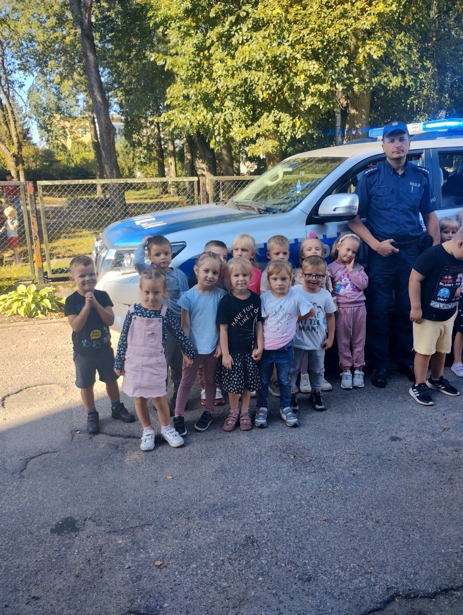 Dnia 28.09.2023r.nasze przedszkolaki miały okazję spotkać się z policjantami. Podczas spotkania przedszkolaki przypomniały sobie zasady bezpiecznego poruszania się po drogach, jak reagować w sytuacjach różnych zagrożeń. Goście ostrzegali też przed osobami nieznajomymi z którymi nie wolno rozmawiać oraz wpuszczać ich do domu. Dzieci wysłuchały policyjnych rad oraz zadawały wiele interesujących pytań. Szczególnym zainteresowaniem wśród dzieci cieszyła się prezentacja wyposażenia policyjnego, niezbędnego podczas wykonywania pracy. Mieliśmy ponadto możliwość obejrzenia krótkich filmików w przedszkolu jak bezpiecznie przejść przez jezdnię oraz jakie numery alarmowe powinien znać każdy, aby wezwać pomocy w razie potrzeby.
Dzieci chętnie wysłuchały opowiadań o codziennej pracy policjanta. Spotkanie przebiegało w bardzo miłej atmosferze. Na zakończenie pan policjant wręczył wszystkim dzieciom sześcioletnim odblaski. 
Serdecznie dziękujemy za miłe spotkanie, to spotkanie oraz treści przekazane na pewno na długo pozostaną w naszej pamięci.