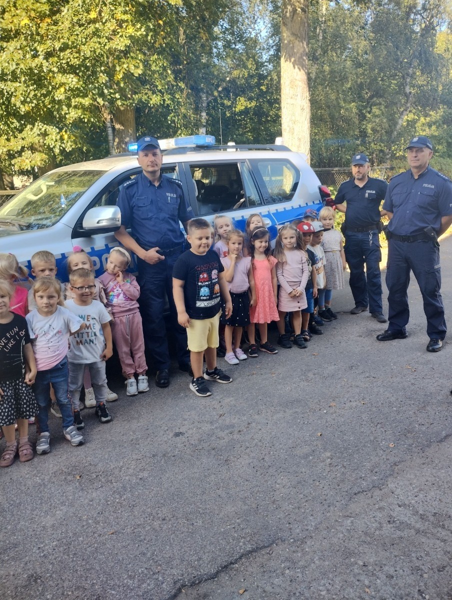 Dnia 28.09.2023r.nasze przedszkolaki miały okazję spotkać się z policjantami. Podczas spotkania przedszkolaki przypomniały sobie zasady bezpiecznego poruszania się po drogach, jak reagować w sytuacjach różnych zagrożeń. Goście ostrzegali też przed osobami nieznajomymi z którymi nie wolno rozmawiać oraz wpuszczać ich do domu. Dzieci wysłuchały policyjnych rad oraz zadawały wiele interesujących pytań. Szczególnym zainteresowaniem wśród dzieci cieszyła się prezentacja wyposażenia policyjnego, niezbędnego podczas wykonywania pracy. Mieliśmy ponadto możliwość obejrzenia krótkich filmików w przedszkolu jak bezpiecznie przejść przez jezdnię oraz jakie numery alarmowe powinien znać każdy, aby wezwać pomocy w razie potrzeby.
Dzieci chętnie wysłuchały opowiadań o codziennej pracy policjanta. Spotkanie przebiegało w bardzo miłej atmosferze. Na zakończenie pan policjant wręczył wszystkim dzieciom sześcioletnim odblaski. 
Serdecznie dziękujemy za miłe spotkanie, to spotkanie oraz treści przekazane na pewno na długo pozostaną w naszej pamięci.