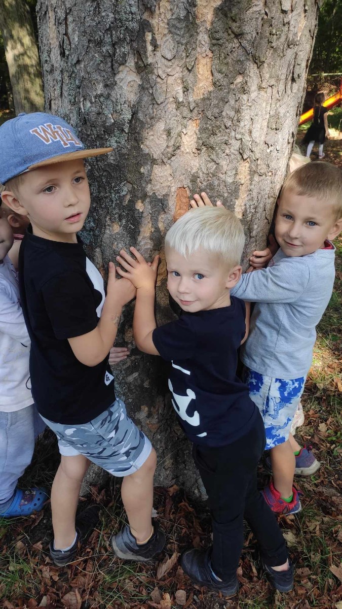 Lato to czas kiedy w lasach pojawiają się pierwsze alerty przeciwpożarowe. Wraz ze wzrostem temperatur ściółka leśna wysycha i coraz łatwiej o pożar lasu.  Tylko w roku 2021 w Polsce wybuchło 3295 pożarów lasów, z czego 2337 tych pożarów powstało z winy człowieka!
	Nasze przedszkolaki we wrześniu przyłączyły się do ogólnopolskiej kampanii PRZYTUL SIĘ DO DRZEWA polegającej na otoczeniu drzew miłością przez przytulenie się do drzewa  i pokazanie, że są one  dla nas ważne.
Kampania PRZYTUL SIĘ DO DRZEWA miała  na  celu zwrócenie uwagi na bezpieczne i mądre poruszanie się po lasach, uczulenie  na rzeczy, które mogą nieświadomie doprowadzić do pożaru.
