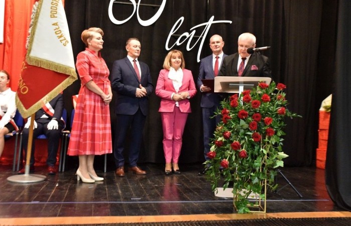 20 października świętowaliśmy Jubileusz 60-lecia Szkoły Podstawowej nr 2 w Pasłęku. Był to dla nas szczególny dzień, czas, w którym w symboliczny sposób przenieśliśmy się do chwili powstania naszej szkoły. Cieszymy się bardzo, że tak ważne dla nas wydarzenie swą obecnością uświetnili: minister Andrzej Śliwka - podsekretarz stanu w Ministerstwie Aktywów Państwowych, Burmistrz Pasłęka Pan Wiesław Śniecikowski, Przewodniczący Rady Miejskiej w Pasłęku Pan Marian Matuszczak, Starosta Powiatu Elbląskiego Pan Maciej Romanowski, wiceburmistrz Pan Marek Sarnowski, dyrektorzy i przedstawiciele instytucji oświatowych, służb mundurowych, działacze stowarzyszeń i związków zawodowych, emeryci oraz liczni absolwenci Szkoły Podstawowej nr 2 w Pasłęku.
Obchody jubileuszu rozpoczęliśmy od posadzenia drzewka przed pomnikiem patrona, Władysława Broniewskiego i przecięcia wstęgi na ławeczce upamiętniającej tę wyjątkową rocznicę. Następnie, już w auli, głos zabrała Pani Dyrektor Agnieszka Cieklińska, dzięki której wspomnienia związane z historią szkoły na nowo odżyły w pamięci zebranych. W pięknych słowach usłyszeliśmy o początkach szkoły, przypomnieliśmy sobie losy ludzi z nią związanych, ich sukcesy i zmagania, dzięki którym my dzisiaj możemy być częścią wyjątkowego miejsca, tak mocno wpisującego się w historię naszego miasta.