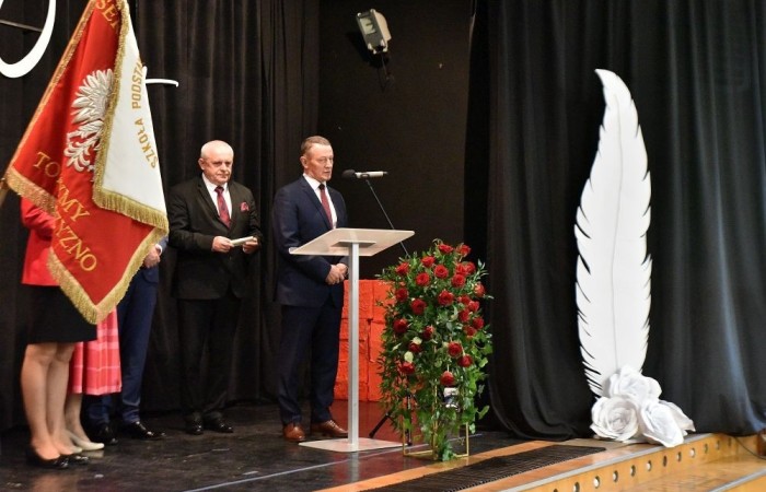 20 października świętowaliśmy Jubileusz 60-lecia Szkoły Podstawowej nr 2 w Pasłęku. Był to dla nas szczególny dzień, czas, w którym w symboliczny sposób przenieśliśmy się do chwili powstania naszej szkoły. Cieszymy się bardzo, że tak ważne dla nas wydarzenie swą obecnością uświetnili: minister Andrzej Śliwka - podsekretarz stanu w Ministerstwie Aktywów Państwowych, Burmistrz Pasłęka Pan Wiesław Śniecikowski, Przewodniczący Rady Miejskiej w Pasłęku Pan Marian Matuszczak, Starosta Powiatu Elbląskiego Pan Maciej Romanowski, wiceburmistrz Pan Marek Sarnowski, dyrektorzy i przedstawiciele instytucji oświatowych, służb mundurowych, działacze stowarzyszeń i związków zawodowych, emeryci oraz liczni absolwenci Szkoły Podstawowej nr 2 w Pasłęku.
Obchody jubileuszu rozpoczęliśmy od posadzenia drzewka przed pomnikiem patrona, Władysława Broniewskiego i przecięcia wstęgi na ławeczce upamiętniającej tę wyjątkową rocznicę. Następnie, już w auli, głos zabrała Pani Dyrektor Agnieszka Cieklińska, dzięki której wspomnienia związane z historią szkoły na nowo odżyły w pamięci zebranych. W pięknych słowach usłyszeliśmy o początkach szkoły, przypomnieliśmy sobie losy ludzi z nią związanych, ich sukcesy i zmagania, dzięki którym my dzisiaj możemy być częścią wyjątkowego miejsca, tak mocno wpisującego się w historię naszego miasta.