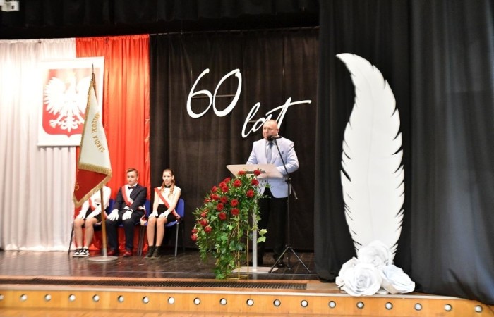 20 października świętowaliśmy Jubileusz 60-lecia Szkoły Podstawowej nr 2 w Pasłęku. Był to dla nas szczególny dzień, czas, w którym w symboliczny sposób przenieśliśmy się do chwili powstania naszej szkoły. Cieszymy się bardzo, że tak ważne dla nas wydarzenie swą obecnością uświetnili: minister Andrzej Śliwka - podsekretarz stanu w Ministerstwie Aktywów Państwowych, Burmistrz Pasłęka Pan Wiesław Śniecikowski, Przewodniczący Rady Miejskiej w Pasłęku Pan Marian Matuszczak, Starosta Powiatu Elbląskiego Pan Maciej Romanowski, wiceburmistrz Pan Marek Sarnowski, dyrektorzy i przedstawiciele instytucji oświatowych, służb mundurowych, działacze stowarzyszeń i związków zawodowych, emeryci oraz liczni absolwenci Szkoły Podstawowej nr 2 w Pasłęku.
Obchody jubileuszu rozpoczęliśmy od posadzenia drzewka przed pomnikiem patrona, Władysława Broniewskiego i przecięcia wstęgi na ławeczce upamiętniającej tę wyjątkową rocznicę. Następnie, już w auli, głos zabrała Pani Dyrektor Agnieszka Cieklińska, dzięki której wspomnienia związane z historią szkoły na nowo odżyły w pamięci zebranych. W pięknych słowach usłyszeliśmy o początkach szkoły, przypomnieliśmy sobie losy ludzi z nią związanych, ich sukcesy i zmagania, dzięki którym my dzisiaj możemy być częścią wyjątkowego miejsca, tak mocno wpisującego się w historię naszego miasta.