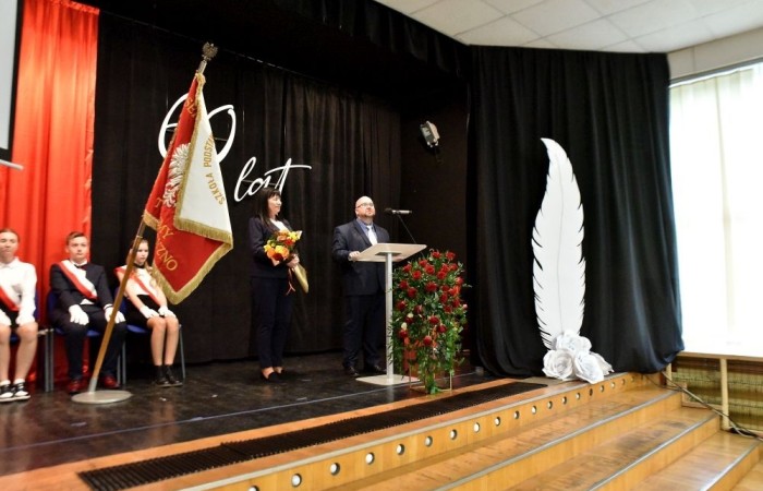 20 października świętowaliśmy Jubileusz 60-lecia Szkoły Podstawowej nr 2 w Pasłęku. Był to dla nas szczególny dzień, czas, w którym w symboliczny sposób przenieśliśmy się do chwili powstania naszej szkoły. Cieszymy się bardzo, że tak ważne dla nas wydarzenie swą obecnością uświetnili: minister Andrzej Śliwka - podsekretarz stanu w Ministerstwie Aktywów Państwowych, Burmistrz Pasłęka Pan Wiesław Śniecikowski, Przewodniczący Rady Miejskiej w Pasłęku Pan Marian Matuszczak, Starosta Powiatu Elbląskiego Pan Maciej Romanowski, wiceburmistrz Pan Marek Sarnowski, dyrektorzy i przedstawiciele instytucji oświatowych, służb mundurowych, działacze stowarzyszeń i związków zawodowych, emeryci oraz liczni absolwenci Szkoły Podstawowej nr 2 w Pasłęku.
Obchody jubileuszu rozpoczęliśmy od posadzenia drzewka przed pomnikiem patrona, Władysława Broniewskiego i przecięcia wstęgi na ławeczce upamiętniającej tę wyjątkową rocznicę. Następnie, już w auli, głos zabrała Pani Dyrektor Agnieszka Cieklińska, dzięki której wspomnienia związane z historią szkoły na nowo odżyły w pamięci zebranych. W pięknych słowach usłyszeliśmy o początkach szkoły, przypomnieliśmy sobie losy ludzi z nią związanych, ich sukcesy i zmagania, dzięki którym my dzisiaj możemy być częścią wyjątkowego miejsca, tak mocno wpisującego się w historię naszego miasta.