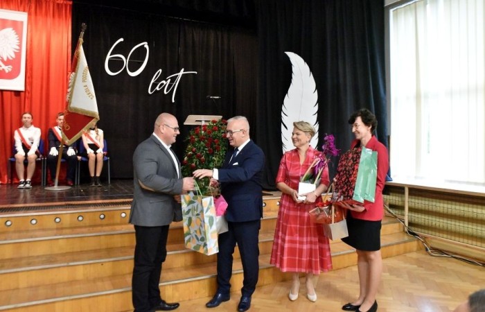 20 października świętowaliśmy Jubileusz 60-lecia Szkoły Podstawowej nr 2 w Pasłęku. Był to dla nas szczególny dzień, czas, w którym w symboliczny sposób przenieśliśmy się do chwili powstania naszej szkoły. Cieszymy się bardzo, że tak ważne dla nas wydarzenie swą obecnością uświetnili: minister Andrzej Śliwka - podsekretarz stanu w Ministerstwie Aktywów Państwowych, Burmistrz Pasłęka Pan Wiesław Śniecikowski, Przewodniczący Rady Miejskiej w Pasłęku Pan Marian Matuszczak, Starosta Powiatu Elbląskiego Pan Maciej Romanowski, wiceburmistrz Pan Marek Sarnowski, dyrektorzy i przedstawiciele instytucji oświatowych, służb mundurowych, działacze stowarzyszeń i związków zawodowych, emeryci oraz liczni absolwenci Szkoły Podstawowej nr 2 w Pasłęku.
Obchody jubileuszu rozpoczęliśmy od posadzenia drzewka przed pomnikiem patrona, Władysława Broniewskiego i przecięcia wstęgi na ławeczce upamiętniającej tę wyjątkową rocznicę. Następnie, już w auli, głos zabrała Pani Dyrektor Agnieszka Cieklińska, dzięki której wspomnienia związane z historią szkoły na nowo odżyły w pamięci zebranych. W pięknych słowach usłyszeliśmy o początkach szkoły, przypomnieliśmy sobie losy ludzi z nią związanych, ich sukcesy i zmagania, dzięki którym my dzisiaj możemy być częścią wyjątkowego miejsca, tak mocno wpisującego się w historię naszego miasta.