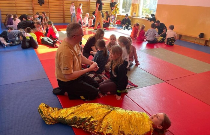 Wczoraj ponownie odwiedzili nas strażacy z OSP Marianka oraz JRG nr 3 w Pasłęku, którym towarzyszyły wolontariuszki z Zespołu Szkół w Pasłęku. Tym razem w spotkaniu uczestniczyli uczniowie klas drugich. Podczas szkolenia dzieci utrwaliły numer alarmowy 112, a także zapoznały się z całą procedurą zgłaszania wypadku i wzywania fachowej pomocy. Uczniowie dowiedzieli się co nieco na temat pracy strażaków, a także tego w jaki sposób opatruje się rany, złamania, udziela pierwszej pomocy, a co najważniejsze mieli okazję do przećwiczenia wszystkiego „na własnej skórze”. Jak widać po zdjęciach i tym razem dzieci były zachwycone. 
To była niezwykle istotna lekcja pomagająca poprzez zabawę i doświadczenia zdobywać nowe bardzo ważne informacje i umiejętności. 