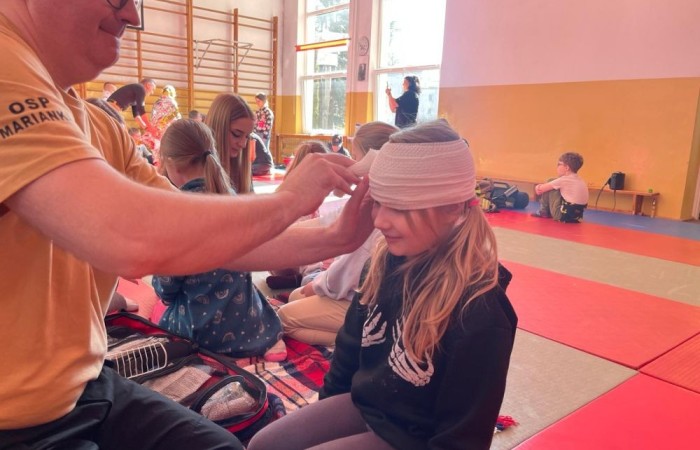 Wczoraj ponownie odwiedzili nas strażacy z OSP Marianka oraz JRG nr 3 w Pasłęku, którym towarzyszyły wolontariuszki z Zespołu Szkół w Pasłęku. Tym razem w spotkaniu uczestniczyli uczniowie klas drugich. Podczas szkolenia dzieci utrwaliły numer alarmowy 112, a także zapoznały się z całą procedurą zgłaszania wypadku i wzywania fachowej pomocy. Uczniowie dowiedzieli się co nieco na temat pracy strażaków, a także tego w jaki sposób opatruje się rany, złamania, udziela pierwszej pomocy, a co najważniejsze mieli okazję do przećwiczenia wszystkiego „na własnej skórze”. Jak widać po zdjęciach i tym razem dzieci były zachwycone. 
To była niezwykle istotna lekcja pomagająca poprzez zabawę i doświadczenia zdobywać nowe bardzo ważne informacje i umiejętności. 