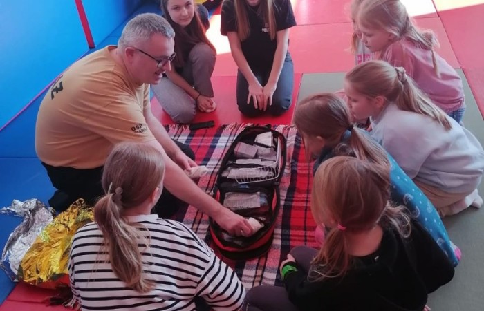 Wczoraj ponownie odwiedzili nas strażacy z OSP Marianka oraz JRG nr 3 w Pasłęku, którym towarzyszyły wolontariuszki z Zespołu Szkół w Pasłęku. Tym razem w spotkaniu uczestniczyli uczniowie klas drugich. Podczas szkolenia dzieci utrwaliły numer alarmowy 112, a także zapoznały się z całą procedurą zgłaszania wypadku i wzywania fachowej pomocy. Uczniowie dowiedzieli się co nieco na temat pracy strażaków, a także tego w jaki sposób opatruje się rany, złamania, udziela pierwszej pomocy, a co najważniejsze mieli okazję do przećwiczenia wszystkiego „na własnej skórze”. Jak widać po zdjęciach i tym razem dzieci były zachwycone. 
To była niezwykle istotna lekcja pomagająca poprzez zabawę i doświadczenia zdobywać nowe bardzo ważne informacje i umiejętności. 