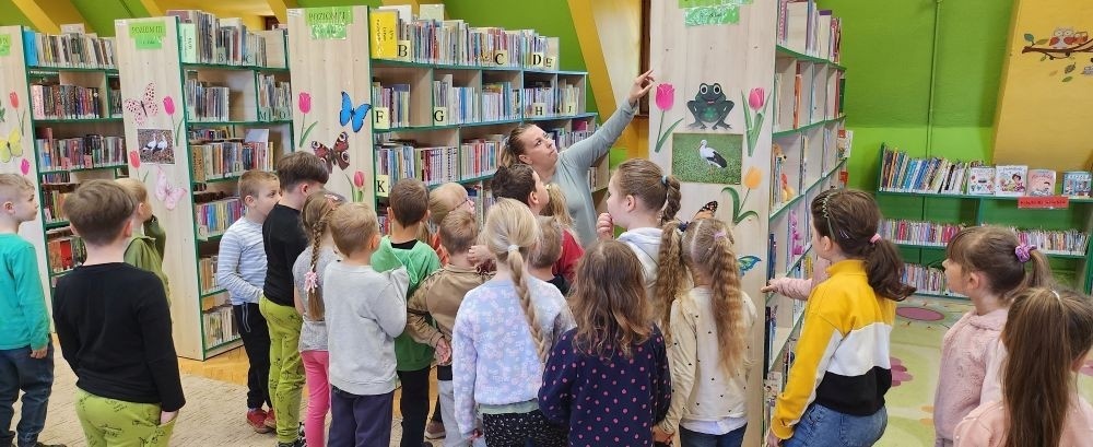 W dniu 7 maja dzieci z grupy „Biedronki „ udały się na lekcję biblioteczną do Biblioteki Publicznej w Pasłęku. Dla wielu z nich była to pierwsza wizyta w takim miejscu. Przedszkolaki zwiedziły bibliotekę, dowiedziały się jaka jest różnica między biblioteką a księgarnią oraz  co należy zrobić, aby stać się czytelnikiem biblioteki. Poznały również zasady właściwego zachowania się w bibliotece oraz czytelni. Dzieci uczestniczyły w lekcji bibliotecznej, podczas której zostały zapoznane ze sposobem powstawania książki. Podczas spotkania zaprezentowana została również literatura dziecięca, którą dzieci mogły swobodnie obejrzeć podczas zabawy. Dużym zainteresowaniem dzieci cieszyło się zwiedzanie Izby Historycznej, w której to miały możliwość zapoznania się z  przedmiotami używanymi  w dawnych czasach. Ku ich zaskoczeniu  zupełnie inaczej kiedyś wyglądało żelazko oraz gofrownica. Na koniec spotkania dzieci miały możliwość pobawienia się zabawkami oraz przemaszerowania się między regałami w celu obejrzenia książeczek. Żegnając się z panią bibliotekarką dzieci zapewniły, że ponownie odwiedzą to ciekawe miejsce razem z rodzicami, by zapisać się do biblioteki i wypożyczać interesujące książki albo po prostu pograć w „planszówki” i miło spędzić  czas.
Bardzo dziękujemy za wspaniała lekcję :)