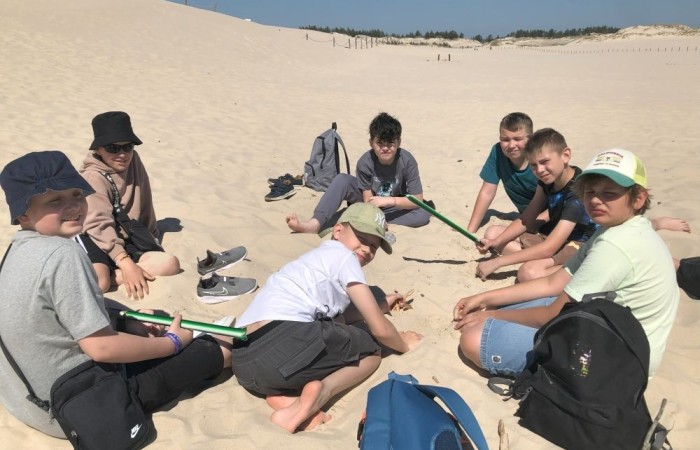 W dniach 15-18 maja 2024 roku uczniowie klas 4A i 5B wybrali się na wycieczkę do Łeby. Oto krótkie podsumowanie ich przygody.
Wizyta w Słowińskim Parku Narodowym była niezapomniana. Ruchome wydmy to unikalne miejsce, gdzie piaskowe pagórki przemieszczają się pod wpływem wiatru. Uczniowie mieli okazję spacerować po tych wydmach i podziwiać piękno natury.
W Łebie Parku czekało na nich wiele atrakcji: Zamek Strachu - dla odważnych, którzy lubią emocje; pojazdy Flinstonów - ciekawa atrakcja dla fanów kultowego serialu, Kopalnia złota - poszukiwanie skarbów; Labirynt magicznych luster - złudzenie nieskończonego lustra; zjeżdżalnie wodne 4 w 1 oraz zjeżdżalnia Boomerang - dla fanów wodnych atrakcji, zjazd na pontonach bez potrzeby przebierania się w stroje kąpielowe, wysokość ślizgu – 10 metrów; Diabelski Młyn, wysoki na 27 metrów wyposażony w 20 gondoli stoi nieopodal naszych zjeżdżalni, widok z góry zapiera dech w piersiach; park trampolin - ogromna przestrzeń, wypełniona parkourem, trampolinami, koszykówką, a także miejscem do robienia salt,  po których bezpiecznie wylądujesz na poduchę; autodrom - atrakcja którą zna niemal każdy! To must-have każdego parku rozrywki.
Uczniowie przemieszczali się po Łebie na melexach, co było wygodnym i ekscytującym środkiem transportu. Na koniec dnia uczniowie odpoczywali w Ośrodku Wypoczynkowym Fregata, gdzie mogli zrelaksować się po pełnym wrażeń dniu.
Wycieczka była udana, a uczniowie wrócili do domu z pięknymi wspomnieniami!