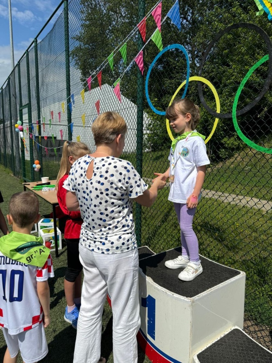 Dzień Dziecka to jeden z najradośniejszych dni, na który czekają młodsze i starsze przedszkolaki. W naszym przedszkolu był to dzień wyjątkowy, pełen życzeń, uśmiechów, radości i niespodzianek. Tego dnia pojawiło się mnóstwo kolorowych HELOWYCH balonów. Od rana panowała radosna atmosfera, a na przedszkolaków czekało wiele atrakcji. 
A wszystko to za sprawą zaprzyjaźnionych Rodziców, ze Stowarzyszenia Przyjaciół, Pasłęckiej Dwójki, którzy zorganizowali w tym dniu Igrzyska Przedszkolaka, zapewniając przy tym wiele atrakcji dzieciom: tj. zapalenie znicza olimpijskiego, wypuszczenie symbolicznie gołębi pokoju, pokaz i parada przedszkolaków, pokaz sportowców, uczniów PS 2 w Pasłęku, reprezentantów sekcji lekkiej atletyki  KS Polonia Pasłęk. Odbyły się konkursy sportowe, zabawy taneczne, oraz smakowity poczęstunek. Nie zabrakło owoców, lodów, słodkości, waty cukrowej i popcornu. Na pożegnanie dzieci otrzymały pamiątkowe medale, dyplomy oraz prezenty.