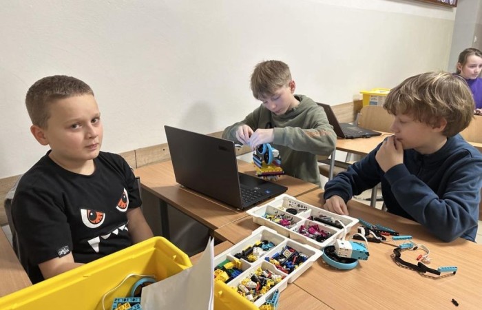 W ramach projektu S.Z.U.M współfinansowanego ze środków Unii Europejskiej systematycznie odbywały się warsztaty komputerowe połączone z robotyką, które zgromadziły liczną grupę entuzjastów nowych technologii i robotyki. Uczestnicy, wyposażeni w zestawy LEGO Spike Prime, mieli okazję rozwijać swoje umiejętności konstrukcyjne oraz programistyczne w atmosferze kreatywnej współpracy i zabawy. Od samego początku zajęć uczestnicy zostali podzieleni na małe zespoły, co sprzyjało integracji oraz wymianie pomysłów. Zadaniem każdej grupy było skonstruowanie robota, który będzie w stanie wykonać określone zadania. Dzięki wsparciu trenera, młodzi inżynierowie nauczyli się, jak krok po kroku budować solidne i funkcjonalne konstrukcje. Był to nie tylko proces twórczy, ale również doskonała lekcja precyzji i cierpliwości. 

Kolejnym etapem warsztatów było programowanie zbudowanych robotów. Uczestnicy, korzystając z intuicyjnego oprogramowania LEGO Spike Prime, mieli okazję zaprogramować swoje konstrukcje do wykonywania różnorodnych ruchów oraz zadań. Wielu z nich po raz pierwszy zetknęło się z programowaniem, co stanowiło nie lada wyzwanie, ale i doskonałą zabawę. Każdy z zespołów osiągnął sukces, ucząc się przy tym podstaw programowania i logiki algorytmicznej.

Zwieńczeniem warsztatów była prezentacja gotowych projektów. Każda grupa z dumą przedstawiła swoje konstrukcje, demonstrując ich funkcjonalność oraz unikalne cechy. Był to moment pełen emocji i satysfakcji, zarówno dla uczestników, jak i dla prowadzących zajęcia.