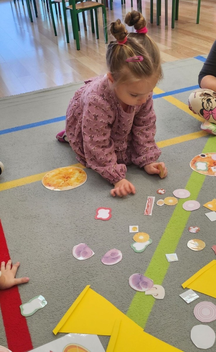 Pizza to ulubiona potrawa nie tylko dorosłych, ale także dzieci. Podczas zajęć przedszkolaki poznały krótką historię pizzy, dowiedziały się, z jakiego kraju pochodzi oraz poznały składniki, które są niezbędne do jej przygotowania. Dzieci w tym dniu miały możliwość komponowania swojej pizzy oraz wykonania jej kawałeczka używając do tego różnych materiałów plastycznych. Podsumowaniem tego pysznego dnia  była konsumpcja pizzy wykonanej przez nasze Panie kucharki. Zapach oregano rozchodził się po całym przedszkolu.

