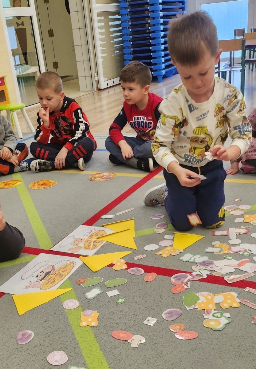 Pizza to ulubiona potrawa nie tylko dorosłych, ale także dzieci. Podczas zajęć przedszkolaki poznały krótką historię pizzy, dowiedziały się, z jakiego kraju pochodzi oraz poznały składniki, które są niezbędne do jej przygotowania. Dzieci w tym dniu miały możliwość komponowania swojej pizzy oraz wykonania jej kawałeczka używając do tego różnych materiałów plastycznych. Podsumowaniem tego pysznego dnia  była konsumpcja pizzy wykonanej przez nasze Panie kucharki. Zapach oregano rozchodził się po całym przedszkolu.
