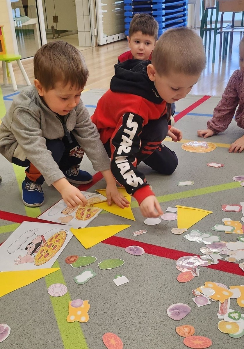 Pizza to ulubiona potrawa nie tylko dorosłych, ale także dzieci. Podczas zajęć przedszkolaki poznały krótką historię pizzy, dowiedziały się, z jakiego kraju pochodzi oraz poznały składniki, które są niezbędne do jej przygotowania. Dzieci w tym dniu miały możliwość komponowania swojej pizzy oraz wykonania jej kawałeczka używając do tego różnych materiałów plastycznych. Podsumowaniem tego pysznego dnia  była konsumpcja pizzy wykonanej przez nasze Panie kucharki. Zapach oregano rozchodził się po całym przedszkolu.
