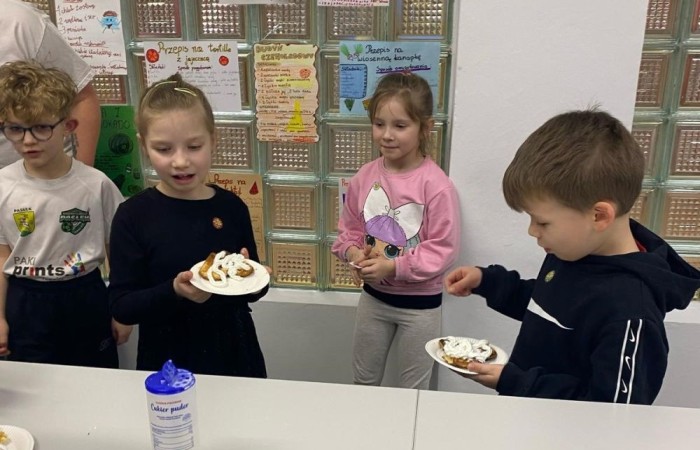 26 lutego w naszej szkole odbył się wyjątkowy DZIEŃ OTWARTY, podczas którego mieliśmy przyjemność gościć przedszkolaków, przyszłych uczniów oraz ich rodziców. Była to doskonała okazja, aby poczuć atmosferę naszej szkoły, poznać jej ofertę edukacyjną i odkryć to, co czyni ją miejscem pełnym pasji, wiedzy i radości.
Zwiedzanie naszej placówki obejmowało sale przedmiotowe, bibliotekę, stołówkę, świetlicę oraz małą salę gimnastyczną, gdzie można było na własnej skórze poczuć rytm codziennego życia naszej szkolnej społeczności.
Na odwiedzających czekało mnóstwo niespodzianek! Zachętą do działania były pieczątki, które najmłodsi otrzymywali w nagrodę za wykonanie przeróżnych zadań. W sali gimnastycznej na uczestników czekały ekscytujące konkurencje sprawnościowe, a w pracowni kulinarnej – pachnące i chrupiące gofry własnej roboty. Młodzi odkrywcy mieli okazję badać świat przez mikroskop, eksperymentować z interaktywnymi robotami Photon oraz brać udział w zajęciach z robotyki. Z kolei miłośnicy sztuki mogli tworzyć piękne dzieła na warsztatach plastycznych i origami, a najmłodsi cieszyli się malowaniem twarzy.
Nie zabrakło także wyzwań dla bystrego umysłu! Gry i zabawy językowe, rebusy oraz polonistyczne łamigłówki rozbudzały wyobraźnię i rozwijały umiejętności językowe. Wesoła „Gimnastyka buzi i języka” sprawiła, że ćwiczenie dykcji stało się czystą przyjemnością. Ogromnym zainteresowaniem cieszyły się również gry planszowe, które dostarczyły mnóstwa radości i emocjonującej rywalizacji. Dodatkowo, zabawy z chustą Klanza okazały się świetnym sposobem na integrację i wspólną zabawę pełną śmiechu.
Aktywne zwiedzanie stało się więc okazją do rozwijania ciekawości świata, nabywania nowych umiejętności, pobudzania w najmłodszych kreatywności oraz odczuwania satysfakcji z osiągniętego sukcesu.