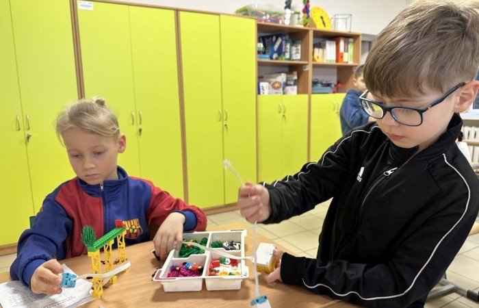 26 lutego w naszej szkole odbył się wyjątkowy DZIEŃ OTWARTY, podczas którego mieliśmy przyjemność gościć przedszkolaków, przyszłych uczniów oraz ich rodziców. Była to doskonała okazja, aby poczuć atmosferę naszej szkoły, poznać jej ofertę edukacyjną i odkryć to, co czyni ją miejscem pełnym pasji, wiedzy i radości.
Zwiedzanie naszej placówki obejmowało sale przedmiotowe, bibliotekę, stołówkę, świetlicę oraz małą salę gimnastyczną, gdzie można było na własnej skórze poczuć rytm codziennego życia naszej szkolnej społeczności.
Na odwiedzających czekało mnóstwo niespodzianek! Zachętą do działania były pieczątki, które najmłodsi otrzymywali w nagrodę za wykonanie przeróżnych zadań. W sali gimnastycznej na uczestników czekały ekscytujące konkurencje sprawnościowe, a w pracowni kulinarnej – pachnące i chrupiące gofry własnej roboty. Młodzi odkrywcy mieli okazję badać świat przez mikroskop, eksperymentować z interaktywnymi robotami Photon oraz brać udział w zajęciach z robotyki. Z kolei miłośnicy sztuki mogli tworzyć piękne dzieła na warsztatach plastycznych i origami, a najmłodsi cieszyli się malowaniem twarzy.
Nie zabrakło także wyzwań dla bystrego umysłu! Gry i zabawy językowe, rebusy oraz polonistyczne łamigłówki rozbudzały wyobraźnię i rozwijały umiejętności językowe. Wesoła „Gimnastyka buzi i języka” sprawiła, że ćwiczenie dykcji stało się czystą przyjemnością. Ogromnym zainteresowaniem cieszyły się również gry planszowe, które dostarczyły mnóstwa radości i emocjonującej rywalizacji. Dodatkowo, zabawy z chustą Klanza okazały się świetnym sposobem na integrację i wspólną zabawę pełną śmiechu.
Aktywne zwiedzanie stało się więc okazją do rozwijania ciekawości świata, nabywania nowych umiejętności, pobudzania w najmłodszych kreatywności oraz odczuwania satysfakcji z osiągniętego sukcesu.