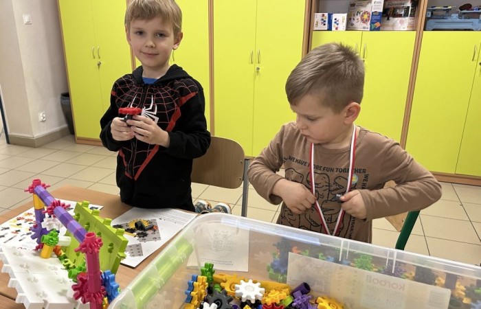 26 lutego w naszej szkole odbył się wyjątkowy DZIEŃ OTWARTY, podczas którego mieliśmy przyjemność gościć przedszkolaków, przyszłych uczniów oraz ich rodziców. Była to doskonała okazja, aby poczuć atmosferę naszej szkoły, poznać jej ofertę edukacyjną i odkryć to, co czyni ją miejscem pełnym pasji, wiedzy i radości.
Zwiedzanie naszej placówki obejmowało sale przedmiotowe, bibliotekę, stołówkę, świetlicę oraz małą salę gimnastyczną, gdzie można było na własnej skórze poczuć rytm codziennego życia naszej szkolnej społeczności.
Na odwiedzających czekało mnóstwo niespodzianek! Zachętą do działania były pieczątki, które najmłodsi otrzymywali w nagrodę za wykonanie przeróżnych zadań. W sali gimnastycznej na uczestników czekały ekscytujące konkurencje sprawnościowe, a w pracowni kulinarnej – pachnące i chrupiące gofry własnej roboty. Młodzi odkrywcy mieli okazję badać świat przez mikroskop, eksperymentować z interaktywnymi robotami Photon oraz brać udział w zajęciach z robotyki. Z kolei miłośnicy sztuki mogli tworzyć piękne dzieła na warsztatach plastycznych i origami, a najmłodsi cieszyli się malowaniem twarzy.
Nie zabrakło także wyzwań dla bystrego umysłu! Gry i zabawy językowe, rebusy oraz polonistyczne łamigłówki rozbudzały wyobraźnię i rozwijały umiejętności językowe. Wesoła „Gimnastyka buzi i języka” sprawiła, że ćwiczenie dykcji stało się czystą przyjemnością. Ogromnym zainteresowaniem cieszyły się również gry planszowe, które dostarczyły mnóstwa radości i emocjonującej rywalizacji. Dodatkowo, zabawy z chustą Klanza okazały się świetnym sposobem na integrację i wspólną zabawę pełną śmiechu.
Aktywne zwiedzanie stało się więc okazją do rozwijania ciekawości świata, nabywania nowych umiejętności, pobudzania w najmłodszych kreatywności oraz odczuwania satysfakcji z osiągniętego sukcesu.