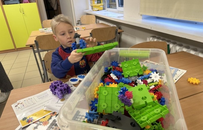 26 lutego w naszej szkole odbył się wyjątkowy DZIEŃ OTWARTY, podczas którego mieliśmy przyjemność gościć przedszkolaków, przyszłych uczniów oraz ich rodziców. Była to doskonała okazja, aby poczuć atmosferę naszej szkoły, poznać jej ofertę edukacyjną i odkryć to, co czyni ją miejscem pełnym pasji, wiedzy i radości.
Zwiedzanie naszej placówki obejmowało sale przedmiotowe, bibliotekę, stołówkę, świetlicę oraz małą salę gimnastyczną, gdzie można było na własnej skórze poczuć rytm codziennego życia naszej szkolnej społeczności.
Na odwiedzających czekało mnóstwo niespodzianek! Zachętą do działania były pieczątki, które najmłodsi otrzymywali w nagrodę za wykonanie przeróżnych zadań. W sali gimnastycznej na uczestników czekały ekscytujące konkurencje sprawnościowe, a w pracowni kulinarnej – pachnące i chrupiące gofry własnej roboty. Młodzi odkrywcy mieli okazję badać świat przez mikroskop, eksperymentować z interaktywnymi robotami Photon oraz brać udział w zajęciach z robotyki. Z kolei miłośnicy sztuki mogli tworzyć piękne dzieła na warsztatach plastycznych i origami, a najmłodsi cieszyli się malowaniem twarzy.
Nie zabrakło także wyzwań dla bystrego umysłu! Gry i zabawy językowe, rebusy oraz polonistyczne łamigłówki rozbudzały wyobraźnię i rozwijały umiejętności językowe. Wesoła „Gimnastyka buzi i języka” sprawiła, że ćwiczenie dykcji stało się czystą przyjemnością. Ogromnym zainteresowaniem cieszyły się również gry planszowe, które dostarczyły mnóstwa radości i emocjonującej rywalizacji. Dodatkowo, zabawy z chustą Klanza okazały się świetnym sposobem na integrację i wspólną zabawę pełną śmiechu.
Aktywne zwiedzanie stało się więc okazją do rozwijania ciekawości świata, nabywania nowych umiejętności, pobudzania w najmłodszych kreatywności oraz odczuwania satysfakcji z osiągniętego sukcesu.