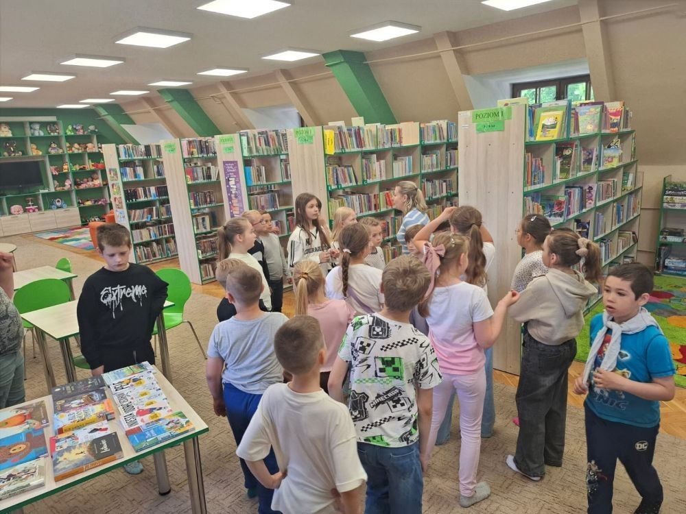 29 maja uczniowie klasy 2a wzięli udział w wycieczce do Biblioteki Publicznej w Pasłęku, gdzie uczestniczyli w ciekawej lekcji bibliotecznej. Pani bibliotekarka przygotowała dla dzieci zajęcia dotyczące lektury „Karolcia”. Uczniowie z dużym zaangażowaniem rozwiązywali łamigłówki, a następnie sprawdzili swoją wiedzę, biorąc udział w teleturnieju. Po części edukacyjnej przyszedł czas na ruch i zabawę. Dzieci uczestniczyły w zawodach w skokach w workach oraz poszukiwały zaginionego koralika Karolci. To był dzień pełen radości, nauki i ciekawych doświadczeń.
