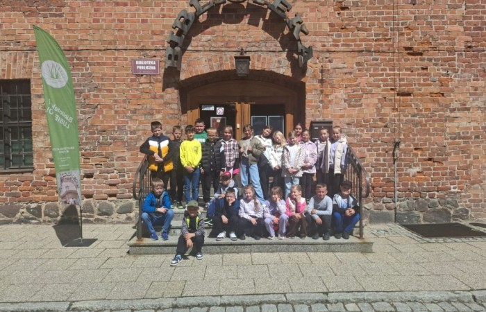 29 maja uczniowie klasy 2a wzięli udział w wycieczce do Biblioteki Publicznej w Pasłęku, gdzie uczestniczyli w ciekawej lekcji bibliotecznej. Pani bibliotekarka przygotowała dla dzieci zajęcia dotyczące lektury „Karolcia”. Uczniowie z dużym zaangażowaniem rozwiązywali łamigłówki, a następnie sprawdzili swoją wiedzę, biorąc udział w teleturnieju. Po części edukacyjnej przyszedł czas na ruch i zabawę. Dzieci uczestniczyły w zawodach w skokach w workach oraz poszukiwały zaginionego koralika Karolci. To był dzień pełen radości, nauki i ciekawych doświadczeń.
