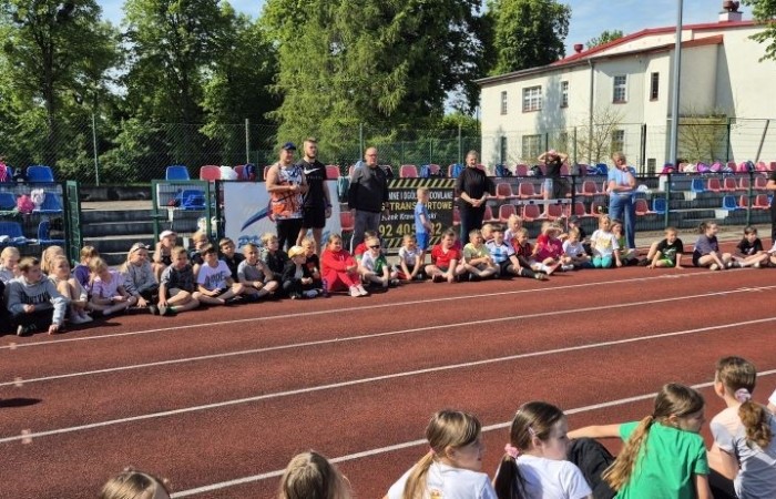Tegoroczne obchody rozpoczęliśmy twórczo – od przygotowania plakatów „Mistrz zdrowia”. Po tej kreatywnej rozgrzewce przyszedł czas na sportowe emocje. Uroczyste otwarcie było tylko wstępem do licznych atrakcji, które czekały na dzieci na stadionie. Dzięki zaangażowaniu pana Piotra Borysewicza i sportowców z KS Polonia Pasłęk sekcji lekkoatletycznej, uczniowie mogli spróbować swoich sił w biegu przez płotki, rzucie piłeczką oraz torze przeszkód w stylu „Ninja Warrior”. Ogromną atrakcją była również wizyta strażaków z JRG 3 w Pasłęku, którzy zapewnili dzieciom wodno-pianową zabawę. Radość na twarzach uczestników mówiła sama za siebie. Na wszystkich zgłodniałych czekały pyszności, w tym słodka wata cukrowa, serwowana przez Panie z Koła Gospodyń Wiejskich w Borzynowie. Szczególne podziękowania kierujemy do niezastąpionych Rodziców – za wsparcie organizacyjne, opiekę podczas wydarzenia oraz przygotowanie dodatkowych atrakcji: plenerowego studia malowania twarzy i tatuaży. Na zakończenie nikt nie wyszedł z pustymi rękami – niezależnie od wyników konkursów każdy uczeń otrzymał drobny upominek i medal. To wyjątkowe święto pełne radości i zabawy już za nami, więc zaczynamy odliczanie do kolejnego Dnia Dziecka!