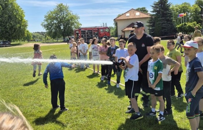 Tegoroczne obchody rozpoczęliśmy twórczo – od przygotowania plakatów „Mistrz zdrowia”. Po tej kreatywnej rozgrzewce przyszedł czas na sportowe emocje. Uroczyste otwarcie było tylko wstępem do licznych atrakcji, które czekały na dzieci na stadionie. Dzięki zaangażowaniu pana Piotra Borysewicza i sportowców z KS Polonia Pasłęk sekcji lekkoatletycznej, uczniowie mogli spróbować swoich sił w biegu przez płotki, rzucie piłeczką oraz torze przeszkód w stylu „Ninja Warrior”. Ogromną atrakcją była również wizyta strażaków z JRG 3 w Pasłęku, którzy zapewnili dzieciom wodno-pianową zabawę. Radość na twarzach uczestników mówiła sama za siebie. Na wszystkich zgłodniałych czekały pyszności, w tym słodka wata cukrowa, serwowana przez Panie z Koła Gospodyń Wiejskich w Borzynowie. Szczególne podziękowania kierujemy do niezastąpionych Rodziców – za wsparcie organizacyjne, opiekę podczas wydarzenia oraz przygotowanie dodatkowych atrakcji: plenerowego studia malowania twarzy i tatuaży. Na zakończenie nikt nie wyszedł z pustymi rękami – niezależnie od wyników konkursów każdy uczeń otrzymał drobny upominek i medal. To wyjątkowe święto pełne radości i zabawy już za nami, więc zaczynamy odliczanie do kolejnego Dnia Dziecka!