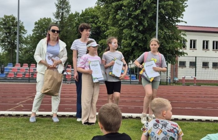 Tegoroczne obchody rozpoczęliśmy twórczo – od przygotowania plakatów „Mistrz zdrowia”. Po tej kreatywnej rozgrzewce przyszedł czas na sportowe emocje. Uroczyste otwarcie było tylko wstępem do licznych atrakcji, które czekały na dzieci na stadionie. Dzięki zaangażowaniu pana Piotra Borysewicza i sportowców z KS Polonia Pasłęk sekcji lekkoatletycznej, uczniowie mogli spróbować swoich sił w biegu przez płotki, rzucie piłeczką oraz torze przeszkód w stylu „Ninja Warrior”. Ogromną atrakcją była również wizyta strażaków z JRG 3 w Pasłęku, którzy zapewnili dzieciom wodno-pianową zabawę. Radość na twarzach uczestników mówiła sama za siebie. Na wszystkich zgłodniałych czekały pyszności, w tym słodka wata cukrowa, serwowana przez Panie z Koła Gospodyń Wiejskich w Borzynowie. Szczególne podziękowania kierujemy do niezastąpionych Rodziców – za wsparcie organizacyjne, opiekę podczas wydarzenia oraz przygotowanie dodatkowych atrakcji: plenerowego studia malowania twarzy i tatuaży. Na zakończenie nikt nie wyszedł z pustymi rękami – niezależnie od wyników konkursów każdy uczeń otrzymał drobny upominek i medal. To wyjątkowe święto pełne radości i zabawy już za nami, więc zaczynamy odliczanie do kolejnego Dnia Dziecka!