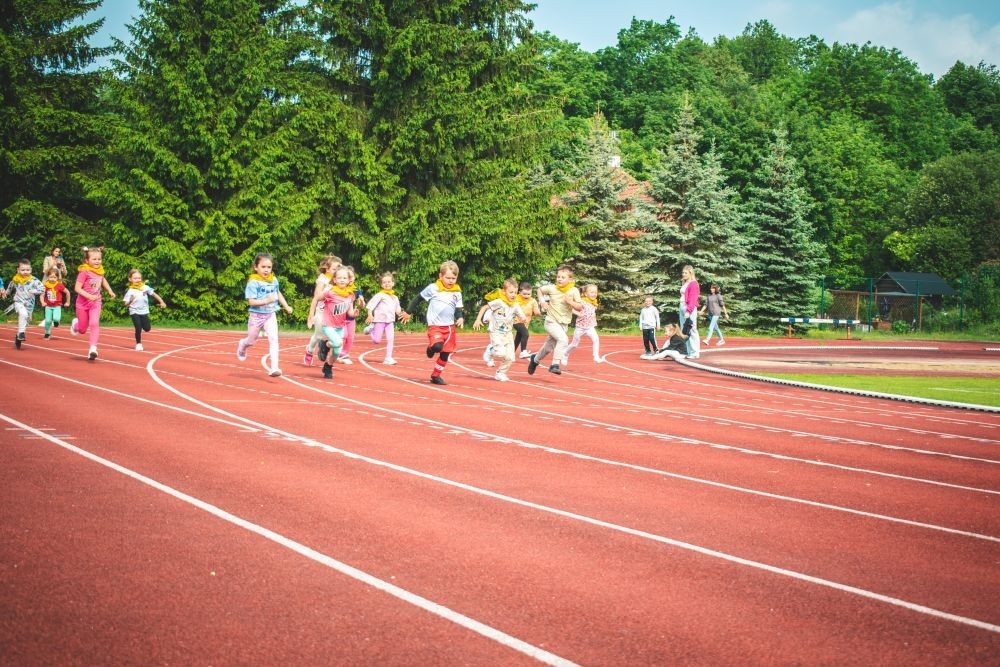2 czerwca nasze przedszkolaki obchodziły Dzień Dziecka wyjątkowo aktywnie!
Na stadionie miejskim, obok różnych zabaw sportowych ,wzięły udział w XI edycji Ogólnopolskiego Maratonu Przedszkolaków „Sprintem do maratonu”.
Zaczęliśmy od przywitania przez p. Dyrektor oraz życzeń z okazji Dnia Dziecka, a później zaczął się –wielki bieg! Każde dziecko z ogromnym zaangażowaniem pokonało wyznaczony dystans, a na mecie czekała na wszystkich zasłużona nagroda – medal, który każdemu osobiście wręczyła p. Wicedyrektor
Po sportowych emocjach przyszedł czas na chwilę wytchnienia i uzupełnienie spalonych kalorii .
Jesteśmy dumne, że nasze przedszkolaki pokonały łącznie aż  3,8 km !
To był niezapomniany dzień pełen ruchu, radości i wspólnej zabawy.