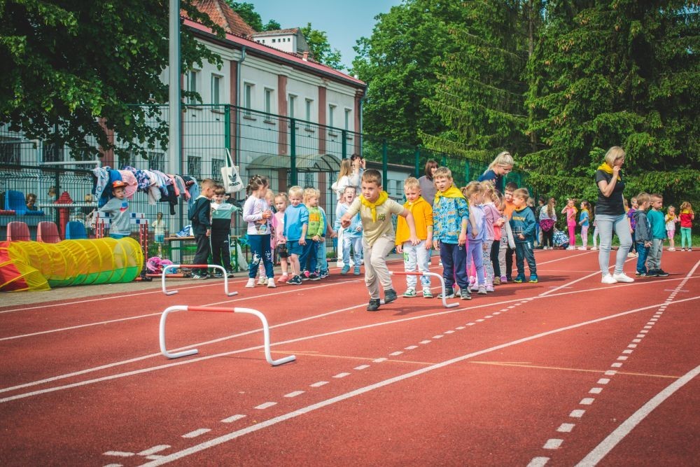 2 czerwca w naszym przedszkolu odbyły się wyjątkowe obchody Dnia Dziecka. W tym roku postawiliśmy na ruch, zabawę i zdrową rywalizację, organizując Sportowy Dzień Dziecka.
Dzień rozpoczęliśmy na Stadionie Miejskim oraz powitania przez panią Dyrektor Agnieszkę Cieklińską i złożenia życzeń z okazji Dnia Dziecka. Następnie wzięliśmy udział w XI edycji Ogólnopolskiego Maratonu Przedszkolaków „Sprintem do maratonu”. Jesteśmy dumne, że nasze przedszkolaki pokonały łącznie aż  3,8 km ! Dalszą część wydarzenia dzieci rywalizowały w różnych konkurencjach: bieg po torze, bieg z przeszkodami, skoki przez płotki czy rzut do celu. Każde dziecko mogło wykazać się sprawnością, zręcznością i współpracą w grupie.
Nie zabrakło także strefy kibica – dzieci dopingowały się nawzajem, a wychowawcy nie szczędzili braw i motywujących okrzyków. Dzięki wsparciu Stowarzyszeniu Przyjaciół Pasłęckiej Dwójki i Koła Gospodyń Wiejskich w Borzynowie w przerwach pomiędzy konkurencjami na dzieci czekały przekąski: owoce, woda, lody, wata cukrowa oraz popcorn.
Na zakończenie wszyscy uczestnicy otrzymali pamiątkowe medale wręczane przez panią Wicedyrektor  Anettę Daszkowską. Radość była ogromna dla dzieci liczyła się przede wszystkim dobra zabawa i wspólnie spędzony czas.
