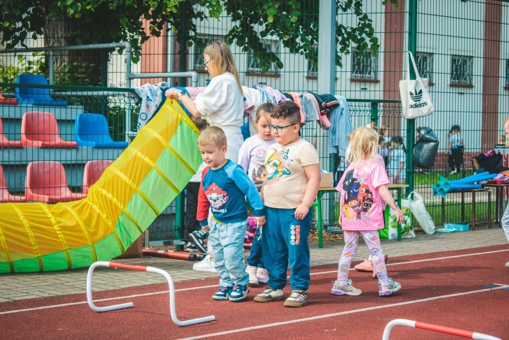 2 czerwca w naszym przedszkolu odbyły się wyjątkowe obchody Dnia Dziecka. W tym roku postawiliśmy na ruch, zabawę i zdrową rywalizację, organizując Sportowy Dzień Dziecka.
Dzień rozpoczęliśmy na Stadionie Miejskim oraz powitania przez panią Dyrektor Agnieszkę Cieklińską i złożenia życzeń z okazji Dnia Dziecka. Następnie wzięliśmy udział w XI edycji Ogólnopolskiego Maratonu Przedszkolaków „Sprintem do maratonu”. Jesteśmy dumne, że nasze przedszkolaki pokonały łącznie aż  3,8 km ! Dalszą część wydarzenia dzieci rywalizowały w różnych konkurencjach: bieg po torze, bieg z przeszkodami, skoki przez płotki czy rzut do celu. Każde dziecko mogło wykazać się sprawnością, zręcznością i współpracą w grupie.
Nie zabrakło także strefy kibica – dzieci dopingowały się nawzajem, a wychowawcy nie szczędzili braw i motywujących okrzyków. Dzięki wsparciu Stowarzyszeniu Przyjaciół Pasłęckiej Dwójki i Koła Gospodyń Wiejskich w Borzynowie w przerwach pomiędzy konkurencjami na dzieci czekały przekąski: owoce, woda, lody, wata cukrowa oraz popcorn.
Na zakończenie wszyscy uczestnicy otrzymali pamiątkowe medale wręczane przez panią Wicedyrektor  Anettę Daszkowską. Radość była ogromna dla dzieci liczyła się przede wszystkim dobra zabawa i wspólnie spędzony czas.
