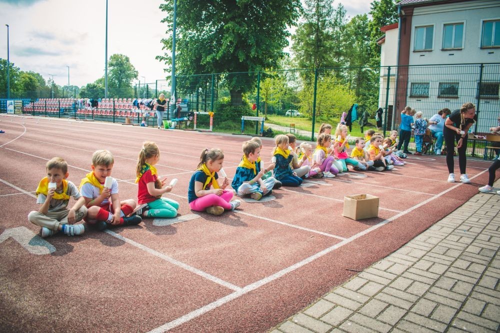 2 czerwca w naszym przedszkolu odbyły się wyjątkowe obchody Dnia Dziecka. W tym roku postawiliśmy na ruch, zabawę i zdrową rywalizację, organizując Sportowy Dzień Dziecka.
Dzień rozpoczęliśmy na Stadionie Miejskim oraz powitania przez panią Dyrektor Agnieszkę Cieklińską i złożenia życzeń z okazji Dnia Dziecka. Następnie wzięliśmy udział w XI edycji Ogólnopolskiego Maratonu Przedszkolaków „Sprintem do maratonu”. Jesteśmy dumne, że nasze przedszkolaki pokonały łącznie aż  3,8 km ! Dalszą część wydarzenia dzieci rywalizowały w różnych konkurencjach: bieg po torze, bieg z przeszkodami, skoki przez płotki czy rzut do celu. Każde dziecko mogło wykazać się sprawnością, zręcznością i współpracą w grupie.
Nie zabrakło także strefy kibica – dzieci dopingowały się nawzajem, a wychowawcy nie szczędzili braw i motywujących okrzyków. Dzięki wsparciu Stowarzyszeniu Przyjaciół Pasłęckiej Dwójki i Koła Gospodyń Wiejskich w Borzynowie w przerwach pomiędzy konkurencjami na dzieci czekały przekąski: owoce, woda, lody, wata cukrowa oraz popcorn.
Na zakończenie wszyscy uczestnicy otrzymali pamiątkowe medale wręczane przez panią Wicedyrektor  Anettę Daszkowską. Radość była ogromna dla dzieci liczyła się przede wszystkim dobra zabawa i wspólnie spędzony czas.
