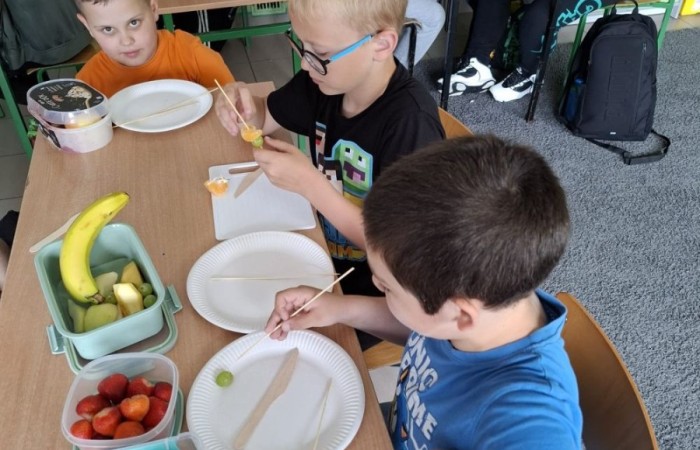 W klasie 2a zrobiło się kolorowo, zdrowo i pysznie. Uczniowie z ogromnym zaangażowaniem przygotowywali owocowe szaszłyki, które zachwycały nie tylko smakiem, ale też wyglądem. Na stołach królowały ulubione owoce dzieci: truskawki, winogrona, banany, kiwi, jabłka i wiele innych. Każdy samodzielnie kroił owoce i tworzył własne, kreatywne kompozycje. To była nie tylko smakowita zabawa, ale również świetna okazja do rozmów o zdrowym odżywianiu oraz nauki współpracy.