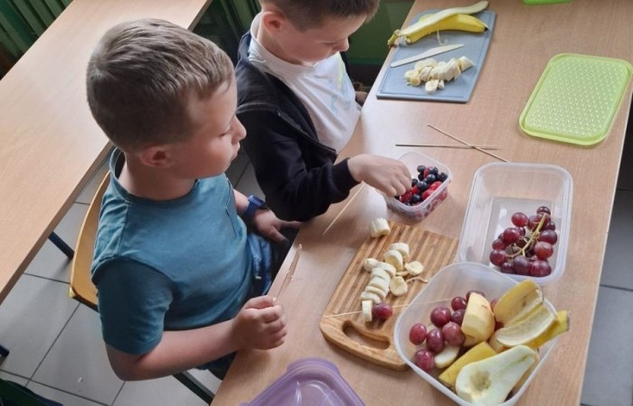 W klasie 2a zrobiło się kolorowo, zdrowo i pysznie. Uczniowie z ogromnym zaangażowaniem przygotowywali owocowe szaszłyki, które zachwycały nie tylko smakiem, ale też wyglądem. Na stołach królowały ulubione owoce dzieci: truskawki, winogrona, banany, kiwi, jabłka i wiele innych. Każdy samodzielnie kroił owoce i tworzył własne, kreatywne kompozycje. To była nie tylko smakowita zabawa, ale również świetna okazja do rozmów o zdrowym odżywianiu oraz nauki współpracy.