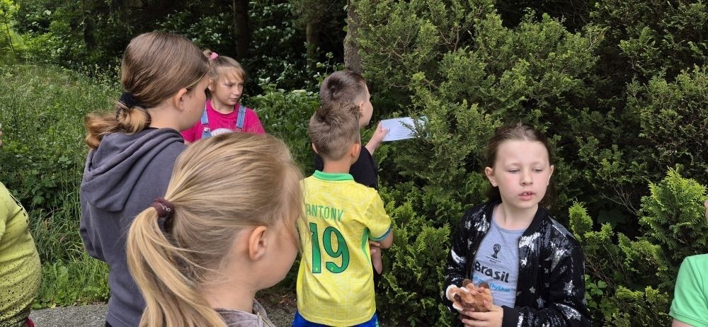 W ramach projektu S.Z.U.M. nasi najmłodsi uczniowie z klas 1-3 wzięli udział w wyjątkowej zabawie edukacyjnej – podchodach ekologicznych. Na terenie szkoły czekały na nich liczne zadania, które nie tylko dostarczyły mnóstwo radości, ale również uczyły, jak dbać o naszą planetę. Dzieci m.in.: rozwiązywały zagadki przyrodnicze, przytulały drzewa, poszukiwały ukrytych figurek zwierząt, wspólnie śpiewały piosenkę o Ziemi, zapisywały ekologiczne hasła – jak pomagać planecie, pokonywały tor przeszkód z ekologicznym przesłaniem. Było radośnie, aktywnie i bardzo zielono.