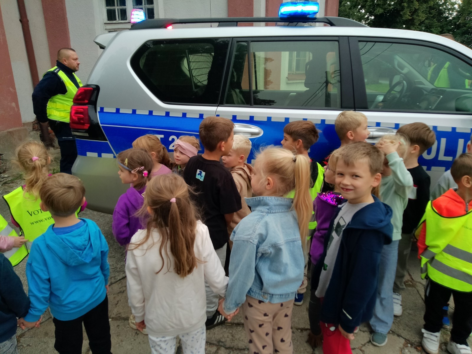 Dzieci z grup starszych Sówki, Leśne skrzaty oraz Biedronki odwiedzili funkcjonariusze policji drogowej , którzy przeprowadzili zajęcia edukacyjne na temat bezpieczeństwa w ruchu ulicznym. Wydarzenie odbyło się w ramach zajęć ,,Moja droga do przedszkola”, której celem jest kształtowanie prawidłowych nawyków i świadomości wśród najmłodszych uczestników ruchu drogowego. Policjanci opowiedzieli przedszkolakom o zasadach bezpiecznego przechodzenia przez jezdnię, znaczeniu znaków drogowych. Dzieci dowiedziały się również, dlaczego ważne jest noszenie odblasków, zwłaszcza jesienią i zimą, gdy wcześniej zapada zmrok.                                
Takie spotkania są bardzo ważne. Dzieci w tym wieku chłoną wiedzę jak gąbka.                  Warto więc już teraz uczyć je zasad, które mogą uratować życie. Przedszkolaki pożegnały policjanta gromkimi brawami i obiecały zawsze pamiętać o zasadach bezpieczeństwa.
Spotkanie z policjantem było nie tylko cenną lekcją, ale też okazją do wzbudzenia w dzieciach zaufania do funkcjonariuszy. To ważny krok w budowaniu poczucia bezpieczeństwa od najmłodszych lat.
