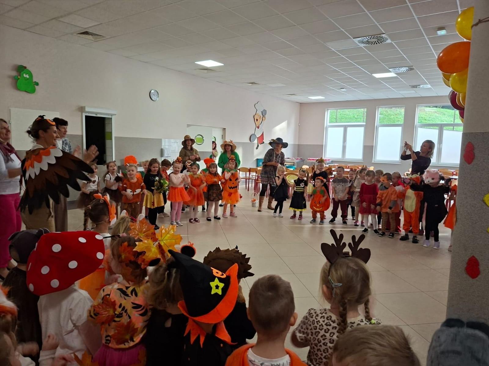 W dniu dzisiejszym w naszym przedszkolu odbył się wyjątkowy i długo wyczekiwany Bal Jesieni. W wydarzeniu wzięły udział wszystkie grupy: Biedronki, Sówki, Leśne Skrzaty oraz Pszczółk oraz dzieci z grup Krasnele i Sówki z Przedszkola Samorządowego nr 1 w Pasłęku, które u nas goszczą od września.
Od samego rana w przedszkolu panowała radosna atmosfera – dzieci przybyły w przepięknych, kolorowych strojach inspirowanych jesienią. Wśród nich można było zobaczyć dynie, jeże, ślimaki, liście, kasztanki, grzybki, wiewiórki, a nawet same Pani Jesienie!
Po powitaniu przez Panie Dyrektor i Wicedyrektor, rozpoczęły się jesienne zabawy i tańce. Wszystkie dzieci wykazały się ogromnym zaangażowaniem, a cała uroczystość odbywała się w duchu radości i wspólnej zabawy.
Nie zabrakło również piosenek i tańców o jesieni – rozbrzmiały takie przeboje z repertuaru dziecięcego Wspólne śpiewanie i tańce przyniosły wszystkim mnóstwo uśmiechu i energii.
Ponadto odbyła się pamiątkowa sesja zdjęciowa w jesiennej scenerii – wśród kolorowych liści, koszy z darami jesieni i szerokich uśmiechów dzieci. 
Jednym z najważniejszych punktów dnia był pokaz jesiennych strojów na niebieskim dywanie. Dzieci z dumą prezentowały swoje przebrania, pozując do zdjęć niczym prawdziwe gwiazdy jesiennego pokazu mody. Publiczność nagradzała ich gromkimi brawami, a w powietrzu czuć było radość i dumę z własnych kreacji.
Bal Jesieni był dniem pełnym barw, muzyki, śmiechu i wspólnej zabawy. Takie wydarzenia integrują dzieci, uczą współpracy, rozwijają kreatywność i pozwalają dostrzec piękno otaczającej nas przyrody. 