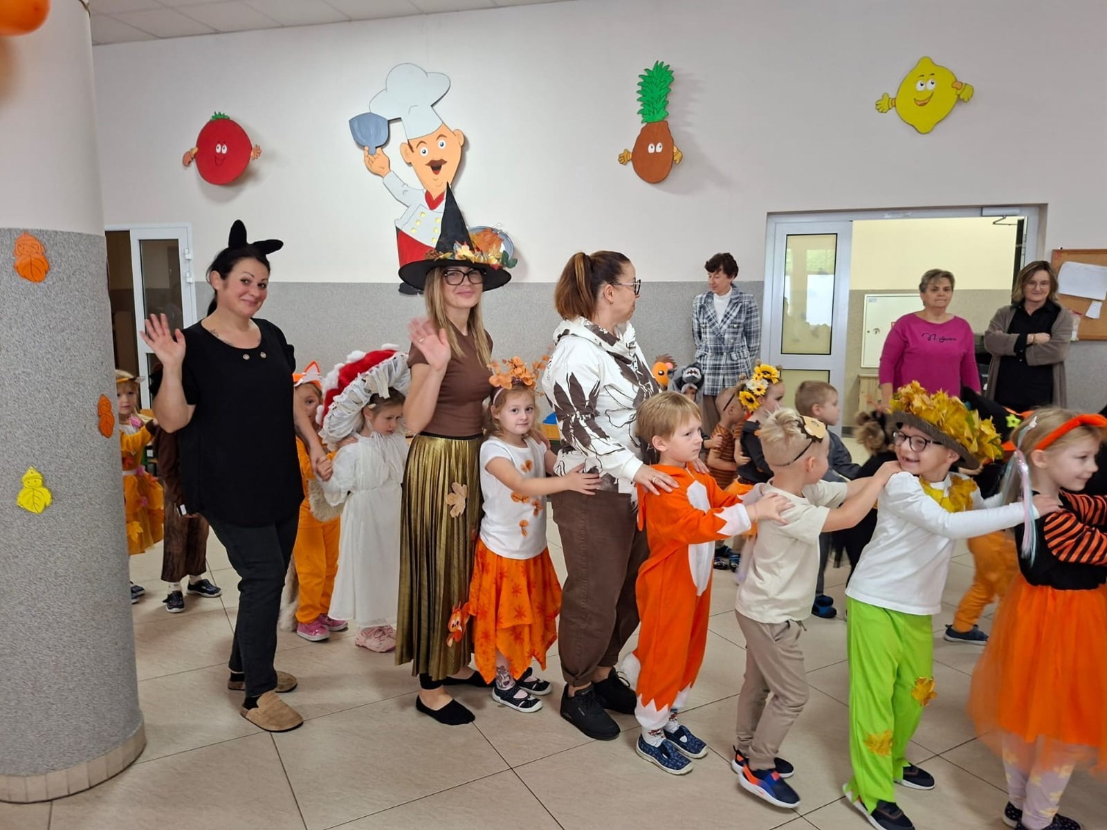 W dniu dzisiejszym w naszym przedszkolu odbył się wyjątkowy i długo wyczekiwany Bal Jesieni. W wydarzeniu wzięły udział wszystkie grupy: Biedronki, Sówki, Leśne Skrzaty oraz Pszczółk oraz dzieci z grup Krasnele i Sówki z Przedszkola Samorządowego nr 1 w Pasłęku, które u nas goszczą od września.
Od samego rana w przedszkolu panowała radosna atmosfera – dzieci przybyły w przepięknych, kolorowych strojach inspirowanych jesienią. Wśród nich można było zobaczyć dynie, jeże, ślimaki, liście, kasztanki, grzybki, wiewiórki, a nawet same Pani Jesienie!
Po powitaniu przez Panie Dyrektor i Wicedyrektor, rozpoczęły się jesienne zabawy i tańce. Wszystkie dzieci wykazały się ogromnym zaangażowaniem, a cała uroczystość odbywała się w duchu radości i wspólnej zabawy.
Nie zabrakło również piosenek i tańców o jesieni – rozbrzmiały takie przeboje z repertuaru dziecięcego Wspólne śpiewanie i tańce przyniosły wszystkim mnóstwo uśmiechu i energii.
Ponadto odbyła się pamiątkowa sesja zdjęciowa w jesiennej scenerii – wśród kolorowych liści, koszy z darami jesieni i szerokich uśmiechów dzieci. 
Jednym z najważniejszych punktów dnia był pokaz jesiennych strojów na niebieskim dywanie. Dzieci z dumą prezentowały swoje przebrania, pozując do zdjęć niczym prawdziwe gwiazdy jesiennego pokazu mody. Publiczność nagradzała ich gromkimi brawami, a w powietrzu czuć było radość i dumę z własnych kreacji.
Bal Jesieni był dniem pełnym barw, muzyki, śmiechu i wspólnej zabawy. Takie wydarzenia integrują dzieci, uczą współpracy, rozwijają kreatywność i pozwalają dostrzec piękno otaczającej nas przyrody. 