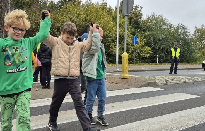 W październiku w naszej szkole odbyły się spotkania uczniów klas I–III z policjantami z Komisariatu Policji w Pasłęku. Podczas zajęć dzieci rozmawiały z funkcjonariuszami o bezpieczeństwie na drodze, uczyły się, jak prawidłowo zachowywać się na przejściu dla pieszych oraz jakie zasady są najważniejsze, by każdego dnia bezpiecznie dotrzeć do szkoły i wrócić do domu.
Uczniowie mieli okazję nie tylko posłuchać, ale również aktywnie ćwiczyć przechodzenie przez pasy pod czujnym okiem policjantów. Było edukacyjnie, ciekawie i bardzo praktycznie.
Serdecznie dziękujemy naszym gościom za poświęcony czas, zaangażowanie i cenne wskazówki, które pomogą naszym uczniom stać się prawdziwymi ekspertami od bezpieczeństwa na drodze.
