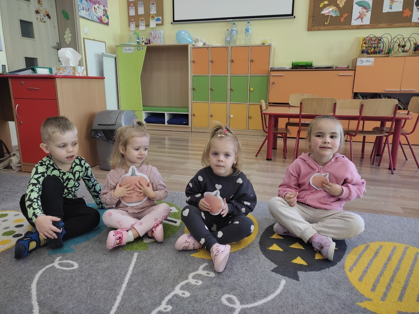 31 października nasze przedszkole zamieniło się w prawdziwą dyniową krainę! W salach królował kolor pomarańczowy, a wszędzie można było zobaczyć uśmiechnięte buzie dzieci i  dynie w różnych kształtach i rozmiarach.Przedszkolaki chętnie brały udział w zabawach muzyczno-ruchowych oraz zajęciach plastycznych z dynią w roli głównej.
Dzieci dowiedziały się, że dynia to nie tylko piękna ozdoba jesieni, ale również zdrowe i smaczne warzywo, z którego można przygotować wiele pysznych potraw.Na zakończenie dnia dzieci otrzymały dyniowe medale oraz pamiątkowe dyplomy,świadczące o ich udziale i zaangażowaniu w obchody tego święta.
To był dzień pełen radości, kolorów ,niezapomnianych wrażeń i jesiennej magii.
