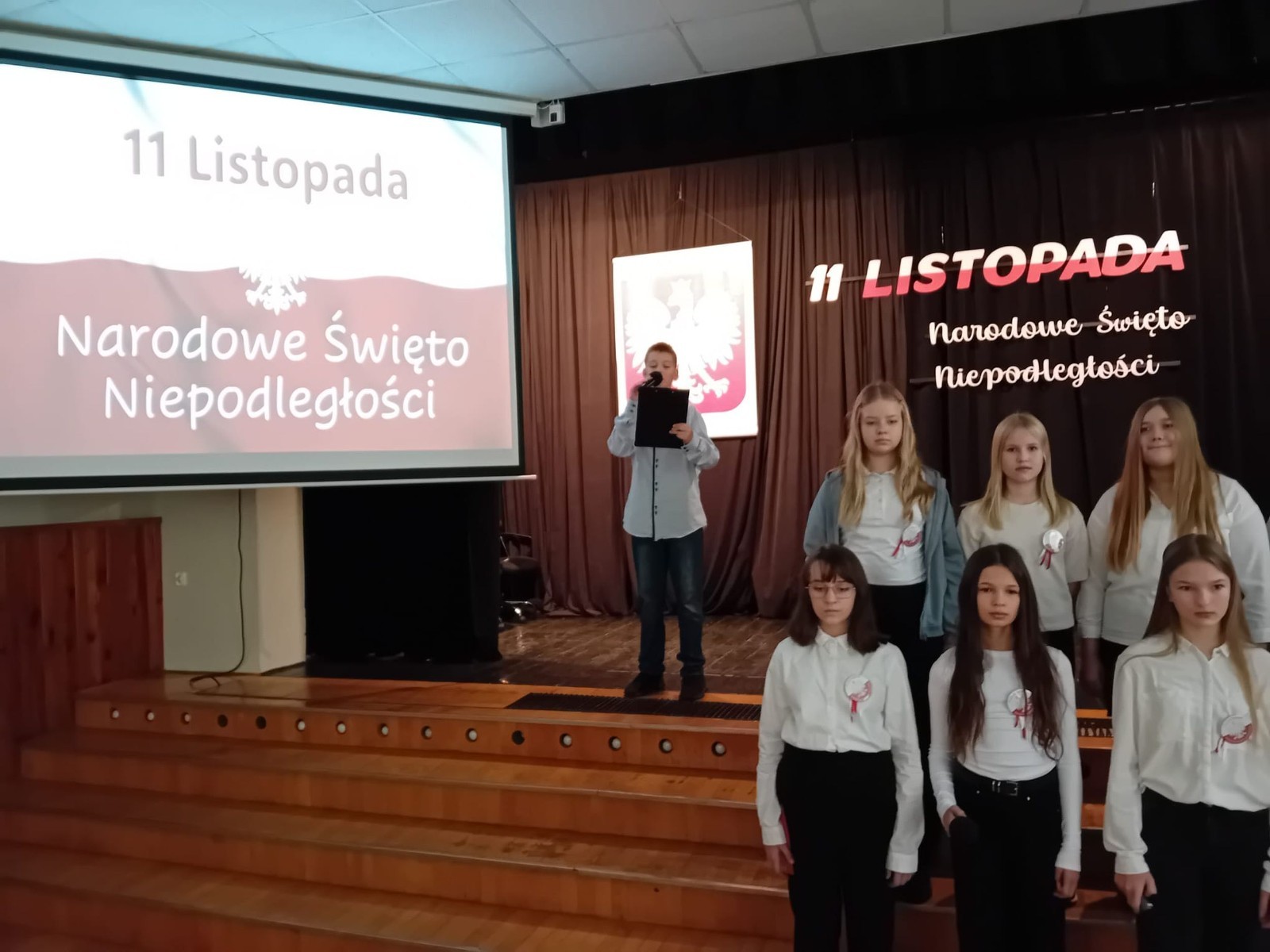 Zbliża się bardzo ważny dzień dla każdego Polaka – 11 Listopada. Nasza szkoła już dziś postanowiła uczcić ten dzień - odbyła się uroczystość z okazji Narodowego Dnia Niepodległości. Był to wyjątkowy czas, podczas którego cała społeczność szkolna mogła wspólnie uczcić jedno z najważniejszych świąt państwowych w Polsce.
Głównym punktem programu był występ uczniów klas szóstych, którzy pod kierunkiem wychowawców, przygotowali wzruszające przedstawienie o tematyce patriotycznej. Młodzi artyści z wielkim zaangażowaniem zaprezentowali najważniejsze wydarzenia, przypominając wszystkim o drodze Polski do wolności oraz o bohaterach narodowych.
Uroczystość uświetnił również występ zespołu wokalnego Forte, prowadzonego przez panią Iwonę Matukiewicz. 
Ważnym momentem wydarzenia było wspólne odśpiewanie hymnu narodowego oraz innych pieśni patriotycznych. Ta chwila połączyła wszystkich uczestników w poczuciu wspólnoty i dumy z bycia Polakami.
Serdecznie dziękujemy wszystkim uczniom, nauczycielom i gościom za udział w uroczystości oraz zaangażowanie w pielęgnowanie pamięci o historii naszego kraju.
