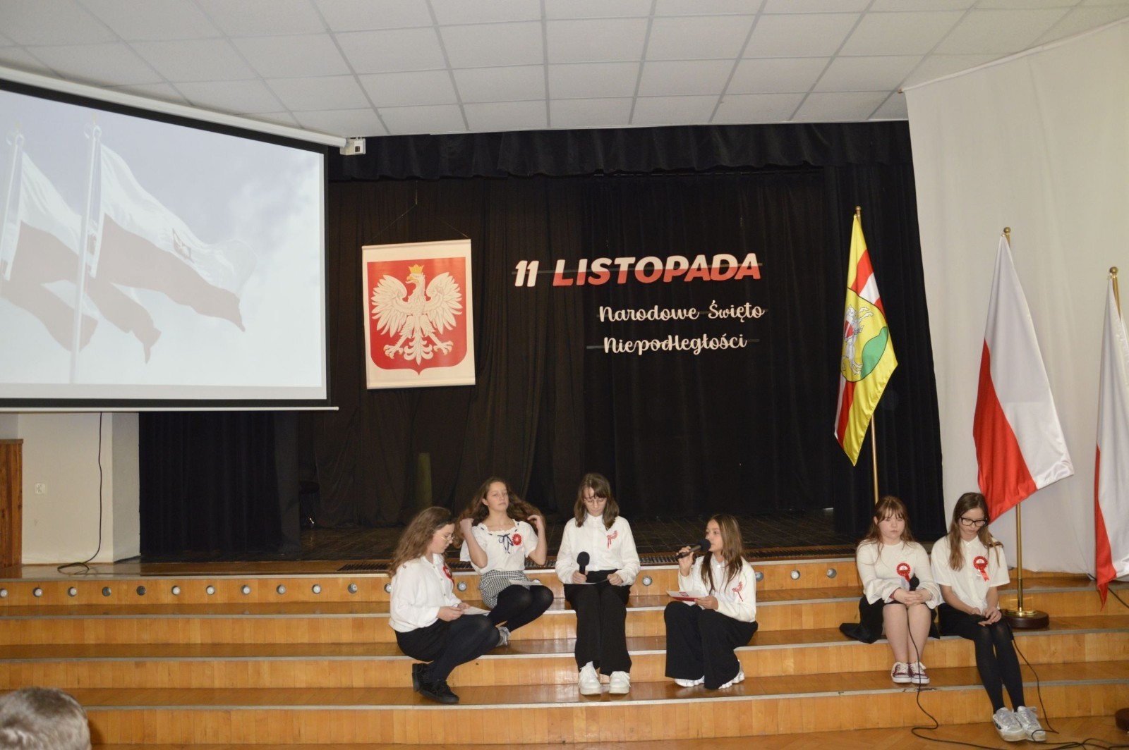 Zbliża się bardzo ważny dzień dla każdego Polaka – 11 Listopada. Nasza szkoła już dziś postanowiła uczcić ten dzień - odbyła się uroczystość z okazji Narodowego Dnia Niepodległości. Był to wyjątkowy czas, podczas którego cała społeczność szkolna mogła wspólnie uczcić jedno z najważniejszych świąt państwowych w Polsce.
Głównym punktem programu był występ uczniów klas szóstych, którzy pod kierunkiem wychowawców, przygotowali wzruszające przedstawienie o tematyce patriotycznej. Młodzi artyści z wielkim zaangażowaniem zaprezentowali najważniejsze wydarzenia, przypominając wszystkim o drodze Polski do wolności oraz o bohaterach narodowych.
Uroczystość uświetnił również występ zespołu wokalnego Forte, prowadzonego przez panią Iwonę Matukiewicz. 
Ważnym momentem wydarzenia było wspólne odśpiewanie hymnu narodowego oraz innych pieśni patriotycznych. Ta chwila połączyła wszystkich uczestników w poczuciu wspólnoty i dumy z bycia Polakami.
Serdecznie dziękujemy wszystkim uczniom, nauczycielom i gościom za udział w uroczystości oraz zaangażowanie w pielęgnowanie pamięci o historii naszego kraju.
