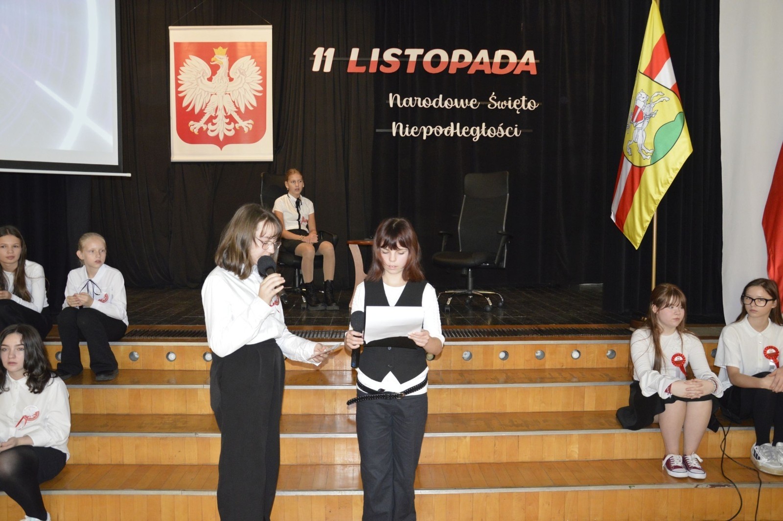 Zbliża się bardzo ważny dzień dla każdego Polaka – 11 Listopada. Nasza szkoła już dziś postanowiła uczcić ten dzień - odbyła się uroczystość z okazji Narodowego Dnia Niepodległości. Był to wyjątkowy czas, podczas którego cała społeczność szkolna mogła wspólnie uczcić jedno z najważniejszych świąt państwowych w Polsce.
Głównym punktem programu był występ uczniów klas szóstych, którzy pod kierunkiem wychowawców, przygotowali wzruszające przedstawienie o tematyce patriotycznej. Młodzi artyści z wielkim zaangażowaniem zaprezentowali najważniejsze wydarzenia, przypominając wszystkim o drodze Polski do wolności oraz o bohaterach narodowych.
Uroczystość uświetnił również występ zespołu wokalnego Forte, prowadzonego przez panią Iwonę Matukiewicz. 
Ważnym momentem wydarzenia było wspólne odśpiewanie hymnu narodowego oraz innych pieśni patriotycznych. Ta chwila połączyła wszystkich uczestników w poczuciu wspólnoty i dumy z bycia Polakami.
Serdecznie dziękujemy wszystkim uczniom, nauczycielom i gościom za udział w uroczystości oraz zaangażowanie w pielęgnowanie pamięci o historii naszego kraju.
