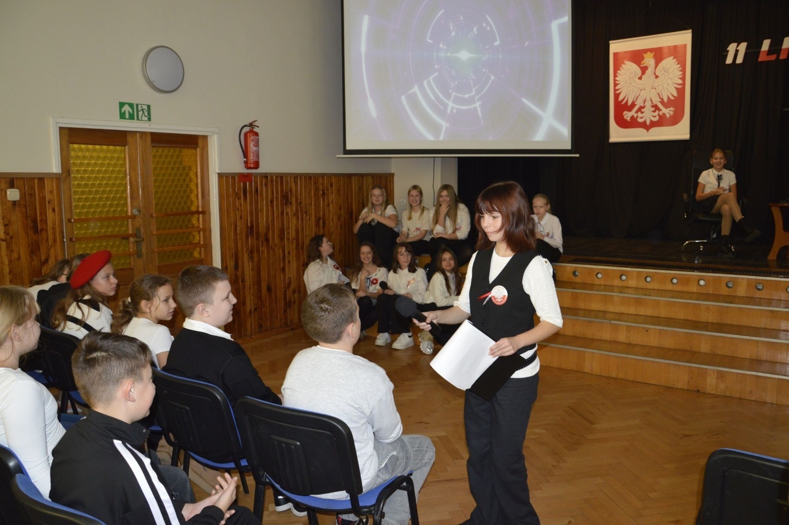 Zbliża się bardzo ważny dzień dla każdego Polaka – 11 Listopada. Nasza szkoła już dziś postanowiła uczcić ten dzień - odbyła się uroczystość z okazji Narodowego Dnia Niepodległości. Był to wyjątkowy czas, podczas którego cała społeczność szkolna mogła wspólnie uczcić jedno z najważniejszych świąt państwowych w Polsce.
Głównym punktem programu był występ uczniów klas szóstych, którzy pod kierunkiem wychowawców, przygotowali wzruszające przedstawienie o tematyce patriotycznej. Młodzi artyści z wielkim zaangażowaniem zaprezentowali najważniejsze wydarzenia, przypominając wszystkim o drodze Polski do wolności oraz o bohaterach narodowych.
Uroczystość uświetnił również występ zespołu wokalnego Forte, prowadzonego przez panią Iwonę Matukiewicz. 
Ważnym momentem wydarzenia było wspólne odśpiewanie hymnu narodowego oraz innych pieśni patriotycznych. Ta chwila połączyła wszystkich uczestników w poczuciu wspólnoty i dumy z bycia Polakami.
Serdecznie dziękujemy wszystkim uczniom, nauczycielom i gościom za udział w uroczystości oraz zaangażowanie w pielęgnowanie pamięci o historii naszego kraju.
