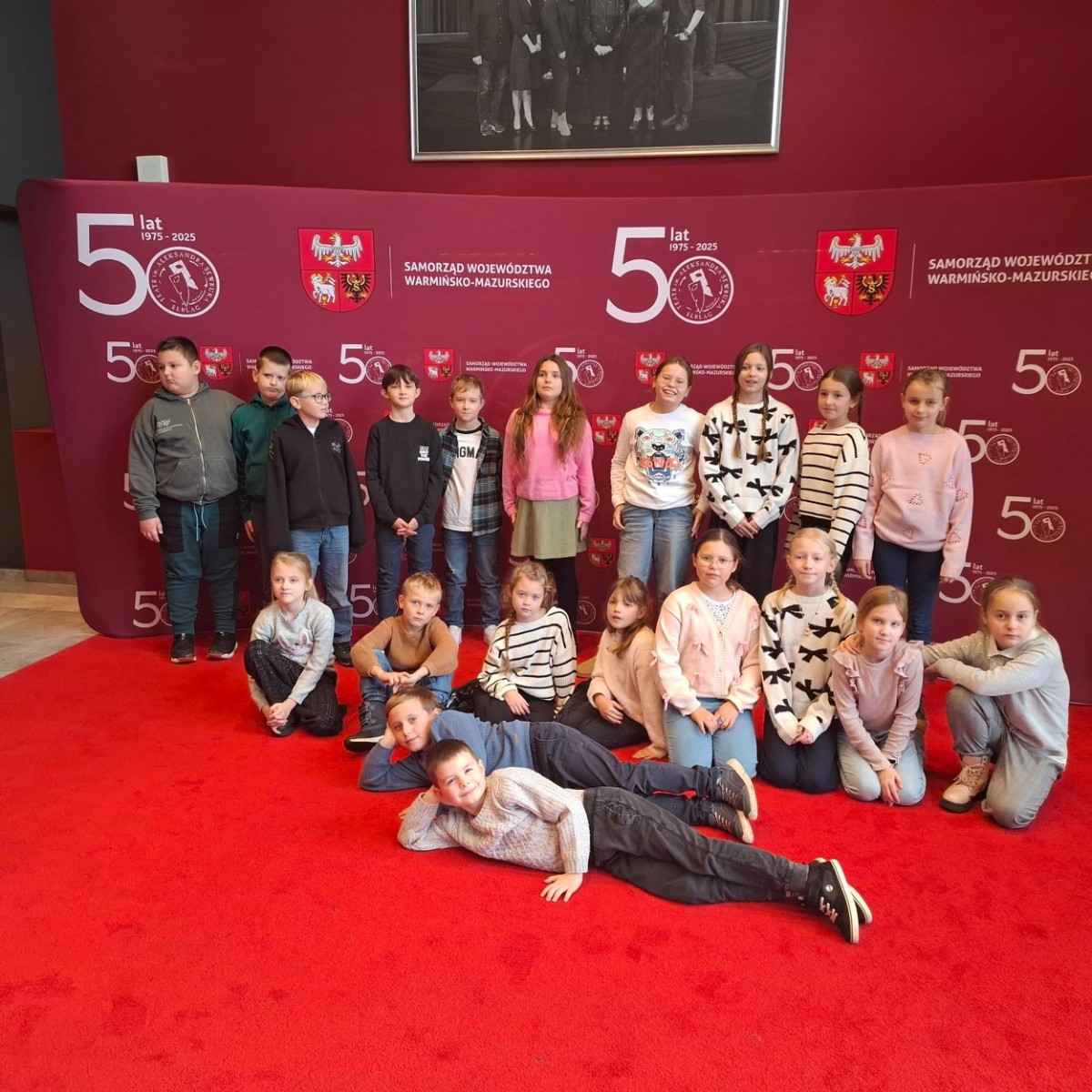 Uczniowie klas trzecich mieli dziś okazję uczestniczyć w wyjątkowym wydarzeniu artystycznym – odwiedzili Teatr im. Aleksandra Sewruka w Elblągu, gdzie obejrzeli spektakl „Dzieci z Bullerbyn”, przygotowany na podstawie uwielbianej przez kolejne pokolenia książki Astrid Lindgren.

Przedstawienie okazało się prawdziwą ucztą teatralną zarówno dla młodych widzów, jak i towarzyszących im nauczycieli. Twórcy spektaklu zadbali o to, by każda scena tętniła energią i kolorami. Na scenie pojawiło się wiele zabawnych historii i wzruszających momentów, które doskonale oddawały klimat klasycznej opowieści o przygodach dzieci z małej, szwedzkiej wioski.

W pamięci uczniów szczególnie zapisał się dynamiczny, pełen pozytywnej energii utwór muzyczny towarzyszący bohaterkom podczas powrotu z zakupów. Jego rytmiczna melodia wywołała szerokie uśmiechy na widowni i – jak przewidujemy – już wkrótce może stać się nieoficjalnym hitem szkolnych przerw.

Wizyta w teatrze była nie tylko okazją do świetnej zabawy, lecz także szansą na kontakt z kulturą w jej najpiękniejszym wydaniu. Uczniowie mogli zobaczyć, jak niezwykła potrafi być magia sceny i jak wiele emocji może przynieść profesjonalnie przygotowany spektakl. Dzisiejszy dzień z pewnością na długo pozostanie w pamięci naszych uczniów jako inspirujące spotkanie ze sztuką.