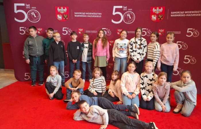 Uczniowie klas trzecich mieli dziś okazję uczestniczyć w wyjątkowym wydarzeniu artystycznym – odwiedzili Teatr im. Aleksandra Sewruka w Elblągu, gdzie obejrzeli spektakl „Dzieci z Bullerbyn”, przygotowany na podstawie uwielbianej przez kolejne pokolenia książki Astrid Lindgren.

Przedstawienie okazało się prawdziwą ucztą teatralną zarówno dla młodych widzów, jak i towarzyszących im nauczycieli. Twórcy spektaklu zadbali o to, by każda scena tętniła energią i kolorami. Na scenie pojawiło się wiele zabawnych historii i wzruszających momentów, które doskonale oddawały klimat klasycznej opowieści o przygodach dzieci z małej, szwedzkiej wioski.

W pamięci uczniów szczególnie zapisał się dynamiczny, pełen pozytywnej energii utwór muzyczny towarzyszący bohaterkom podczas powrotu z zakupów. Jego rytmiczna melodia wywołała szerokie uśmiechy na widowni i – jak przewidujemy – już wkrótce może stać się nieoficjalnym hitem szkolnych przerw.

Wizyta w teatrze była nie tylko okazją do świetnej zabawy, lecz także szansą na kontakt z kulturą w jej najpiękniejszym wydaniu. Uczniowie mogli zobaczyć, jak niezwykła potrafi być magia sceny i jak wiele emocji może przynieść profesjonalnie przygotowany spektakl. Dzisiejszy dzień z pewnością na długo pozostanie w pamięci naszych uczniów jako inspirujące spotkanie ze sztuką.