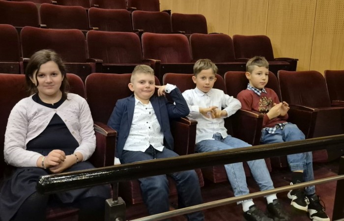 Uczniowie klas trzecich mieli dziś okazję uczestniczyć w wyjątkowym wydarzeniu artystycznym – odwiedzili Teatr im. Aleksandra Sewruka w Elblągu, gdzie obejrzeli spektakl „Dzieci z Bullerbyn”, przygotowany na podstawie uwielbianej przez kolejne pokolenia książki Astrid Lindgren.

Przedstawienie okazało się prawdziwą ucztą teatralną zarówno dla młodych widzów, jak i towarzyszących im nauczycieli. Twórcy spektaklu zadbali o to, by każda scena tętniła energią i kolorami. Na scenie pojawiło się wiele zabawnych historii i wzruszających momentów, które doskonale oddawały klimat klasycznej opowieści o przygodach dzieci z małej, szwedzkiej wioski.

W pamięci uczniów szczególnie zapisał się dynamiczny, pełen pozytywnej energii utwór muzyczny towarzyszący bohaterkom podczas powrotu z zakupów. Jego rytmiczna melodia wywołała szerokie uśmiechy na widowni i – jak przewidujemy – już wkrótce może stać się nieoficjalnym hitem szkolnych przerw.

Wizyta w teatrze była nie tylko okazją do świetnej zabawy, lecz także szansą na kontakt z kulturą w jej najpiękniejszym wydaniu. Uczniowie mogli zobaczyć, jak niezwykła potrafi być magia sceny i jak wiele emocji może przynieść profesjonalnie przygotowany spektakl. Dzisiejszy dzień z pewnością na długo pozostanie w pamięci naszych uczniów jako inspirujące spotkanie ze sztuką.