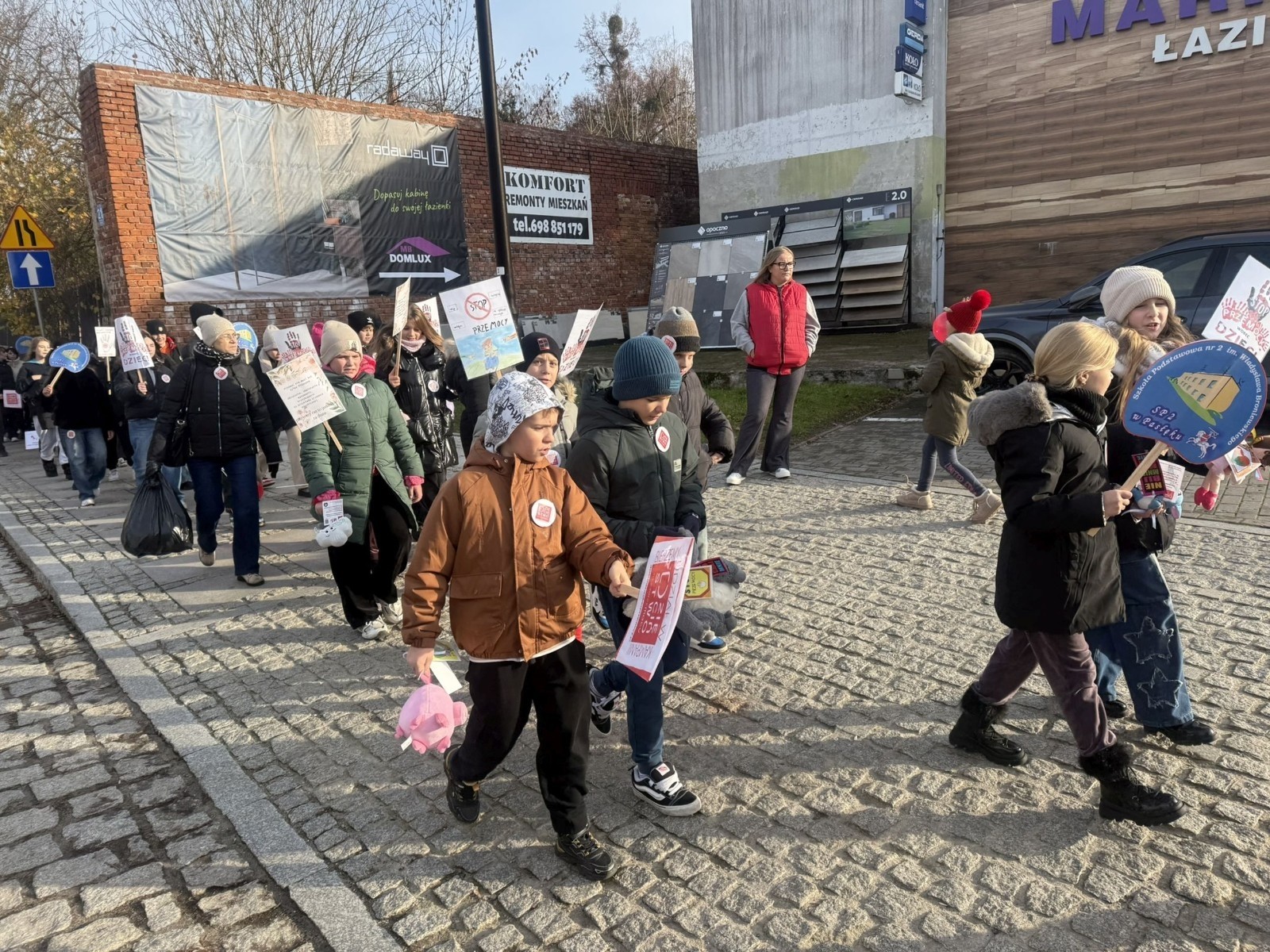 W środę 17.11.2025 nasza szkoła zorganizowała wyjątkowe wydarzenie, które było zaczątkiem podsumowania kampanii „Dzieciństwo bez Przemocy”. Dzień rozpoczął się od radosnego marszu, w którym dzieci grup przedszkolnych z wychowawczyniami oraz uczniowie wraz z nauczycielami przeszli ulicami naszego miasta. Podczas tego wydarzenia dzieci rozdawały mieszkańcom kolorowe maskotki, promując ideę bezpiecznego i szczęśliwego dzieciństwa.
Ważnym punktem dnia było spotkanie w Urzędzie Miasta z panią burmistrz, która serdecznie przyjęła naszych reprezentantów. Rozmowy dotyczyły dalszych działań na rzecz dzieci oraz wspierania inicjatyw mających na celu eliminację przemocy wśród najmłodszych.